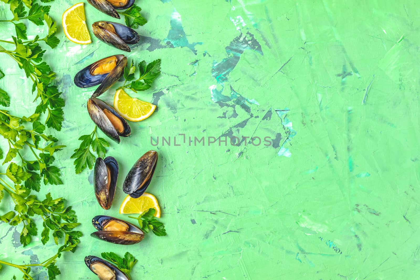 Seafood mussels with lemon and parsley on green concrete table surface, top view, copy space for you text