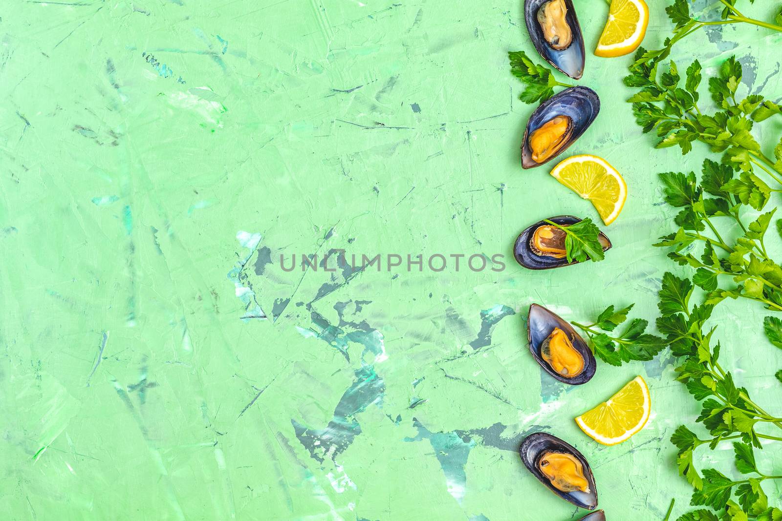 Seafood mussels with lemon and parsley on green concrete table surface, top view, copy space for you text