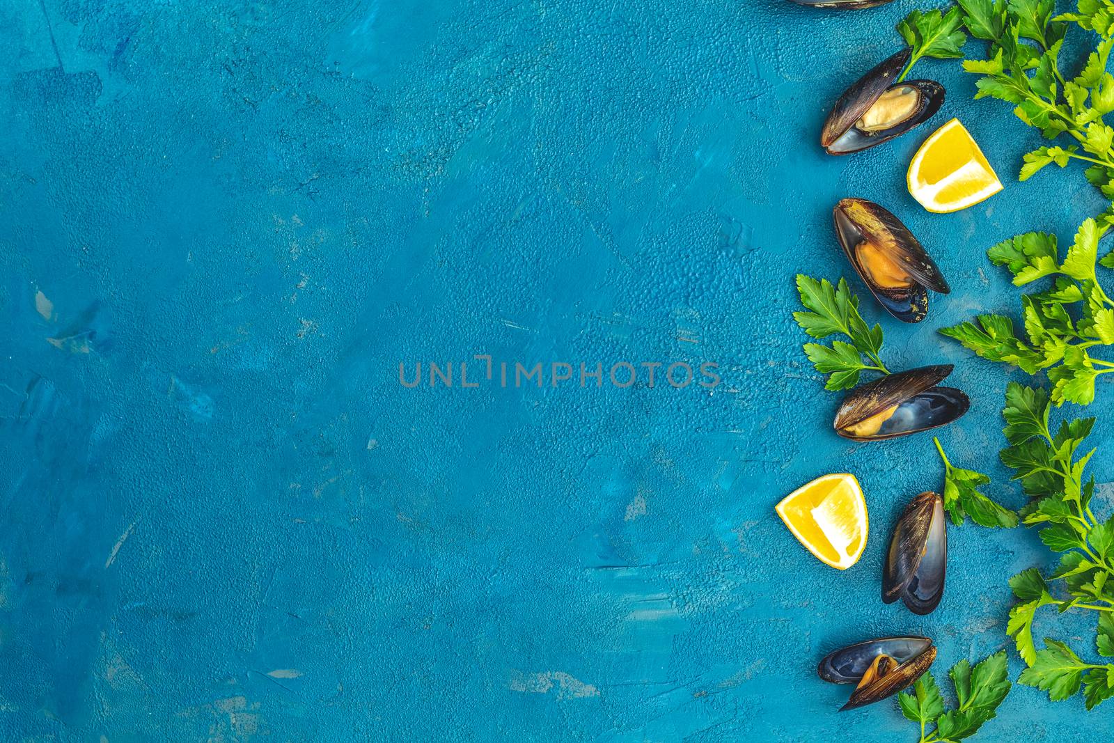 Seafood mussels with lemon and parsley on dark blue concrete table surface, top view, copy space for you text