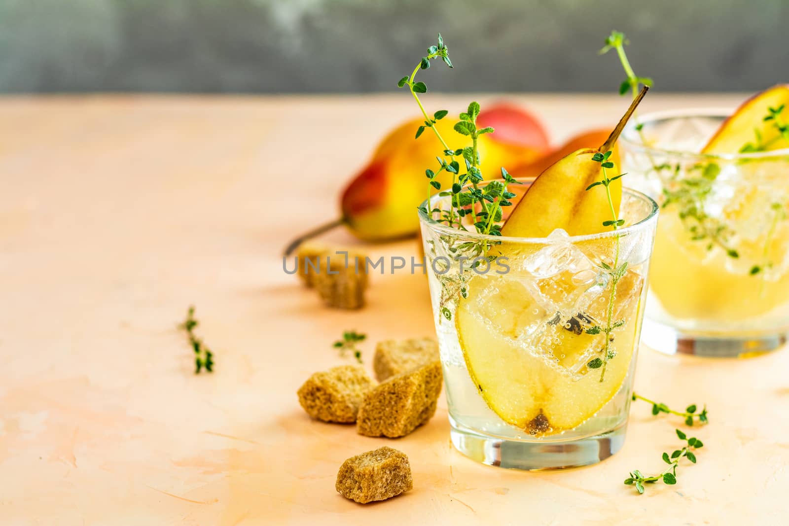 Cold pear white tea with thyme on the wooden background. Festive summer drinks, pear thyme cocktail. Selective focus, space for text.