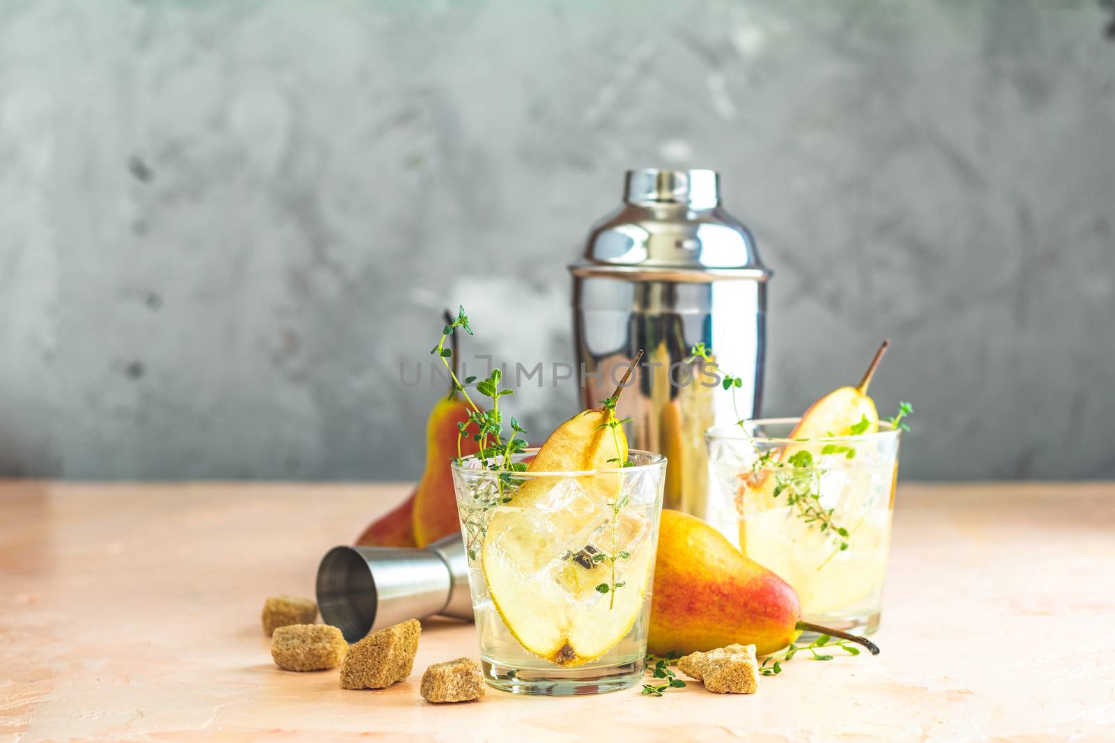 Pear mulled cider with thyme, brown sugar and ice on light concrete surface table