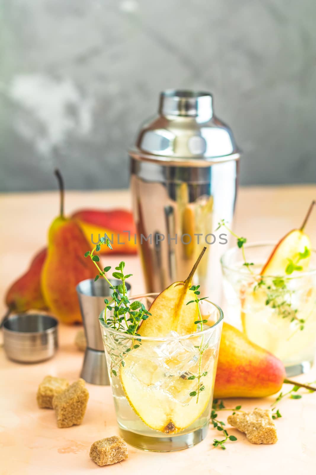 Cold pear white tea with thyme on the pink concrete table background. Festive summer drinks, pear thyme cocktail. Selective focus, space for text