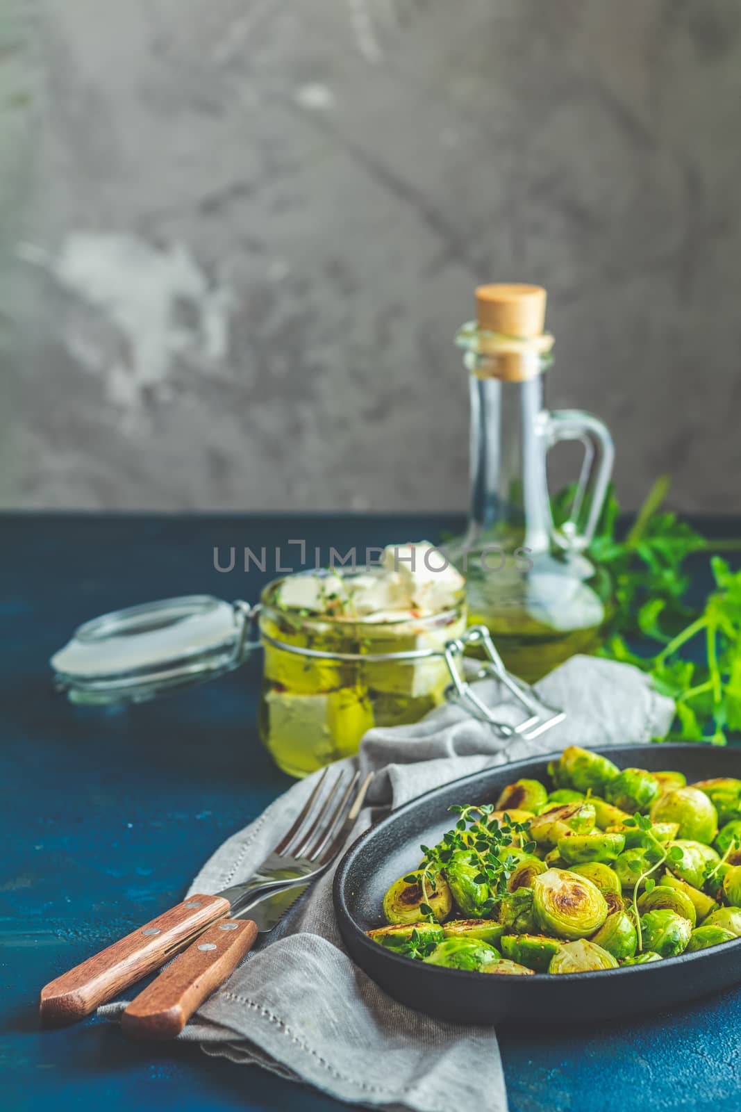 Black plate with delicious roasted Brussels sprouts in served on black plate, dark blue concrete table surface, copy space for you text.