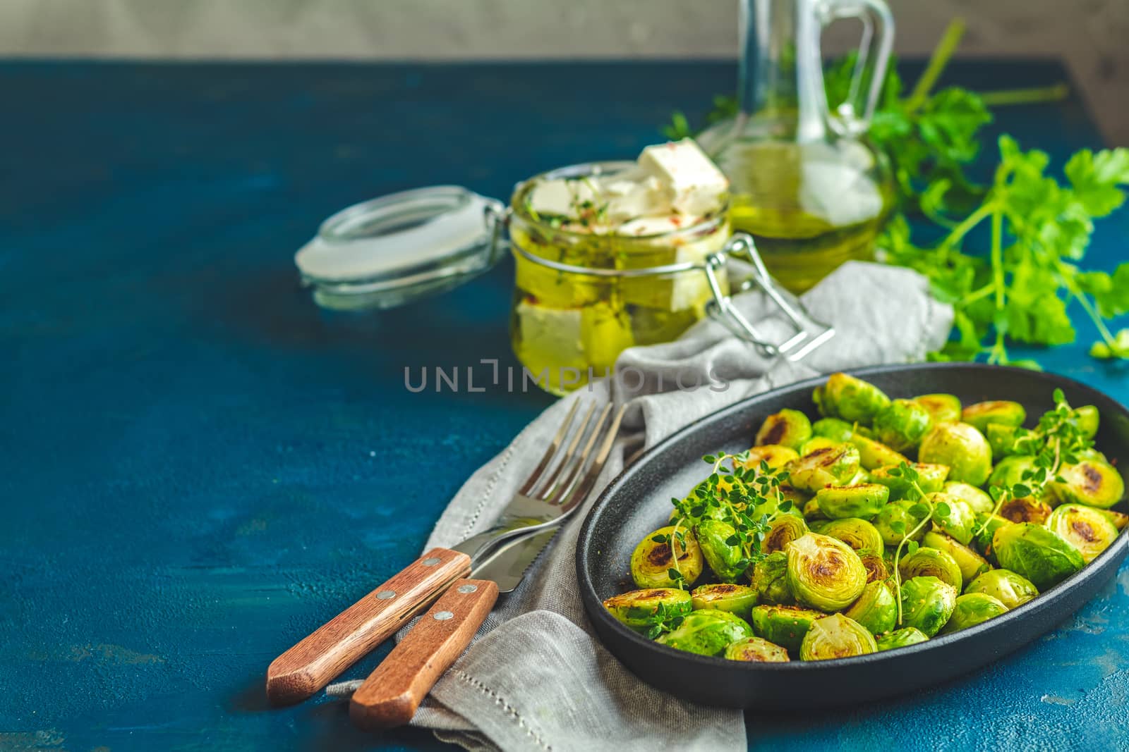 Black plate with delicious roasted. Brussels sprouts in served on black plate, dark blue concrete table surface, copy space for you text.
