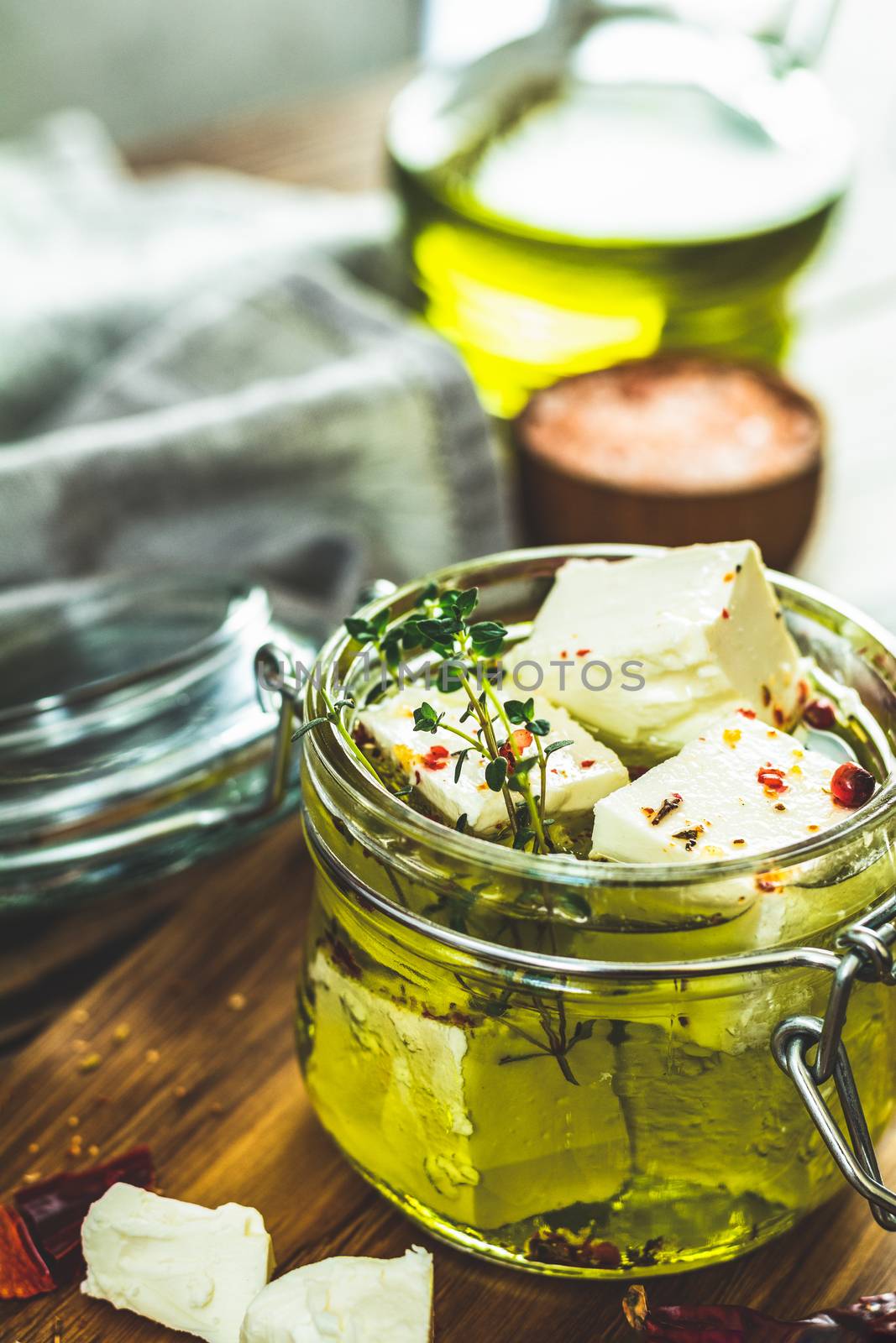Feta cheese marinated in olive oil with fresh herbs in glass jar by ArtSvitlyna