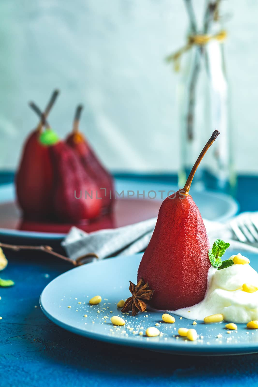 Pears in wine. Traditional dessert pears stewed in red wine with wine sauce on plate on blue concrete surface. Concept for romantic dinner dessert