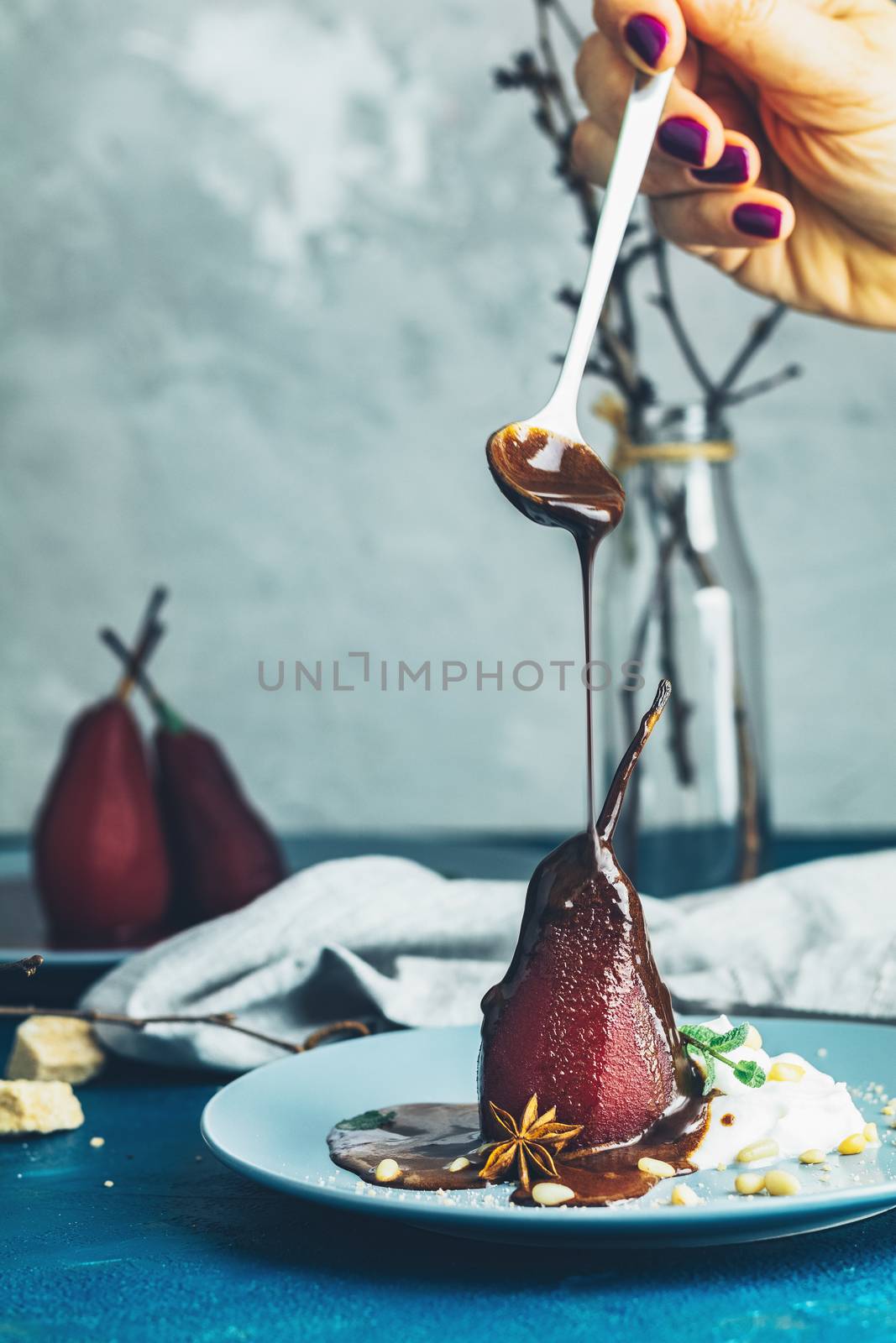 Chocolate sauce pours from a spoon on red pears in wine by ArtSvitlyna