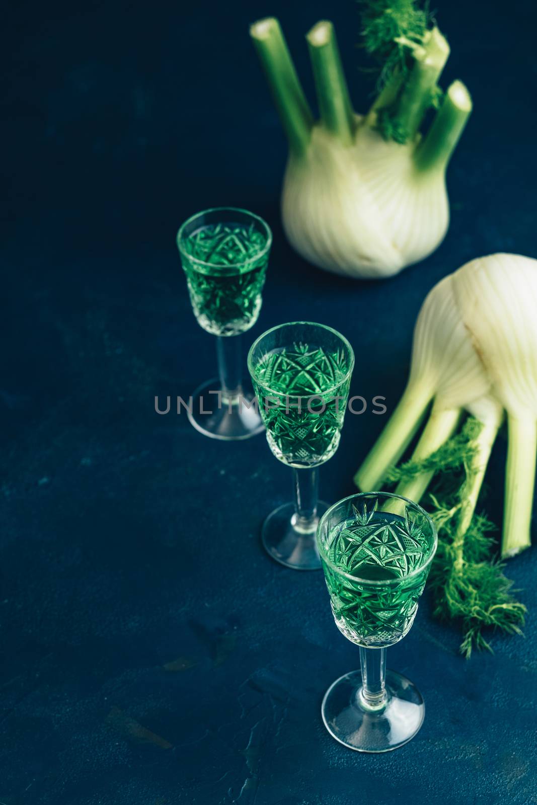 Traditional italian or czech liqueur or bitter with fennel. Three absinthe glass. Dark blue concrete table surface background, copy space for you text.