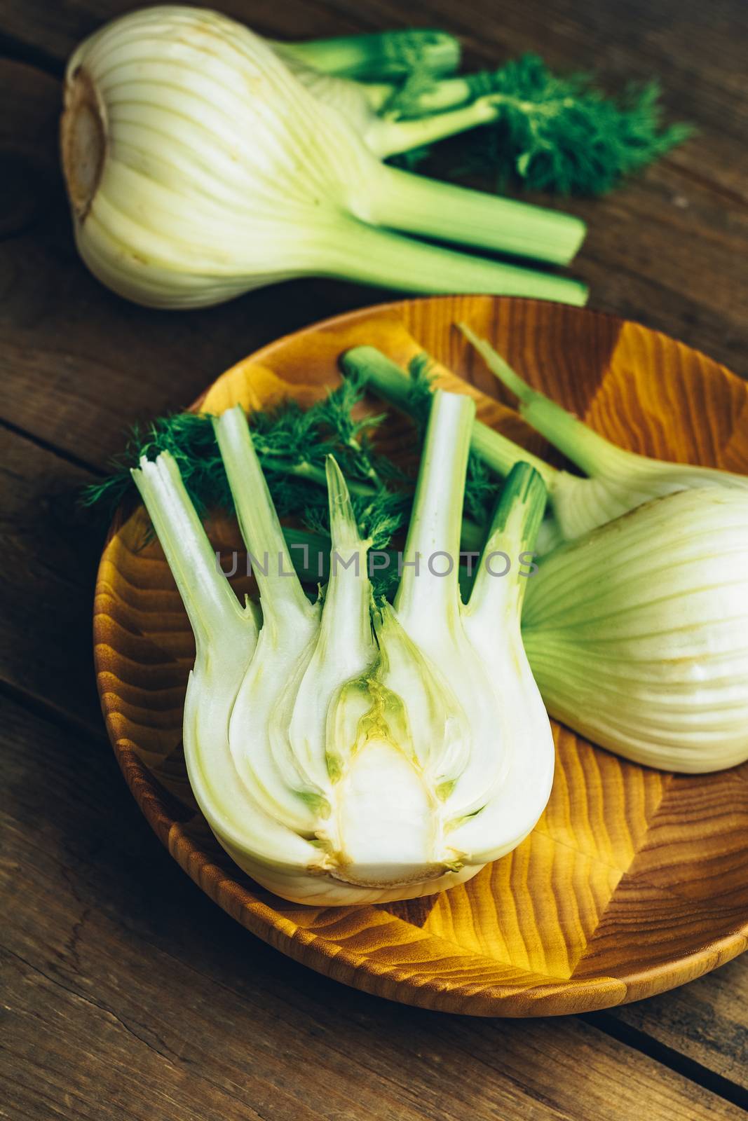 Fresh fennel bulbs in plate on wooden background. by ArtSvitlyna