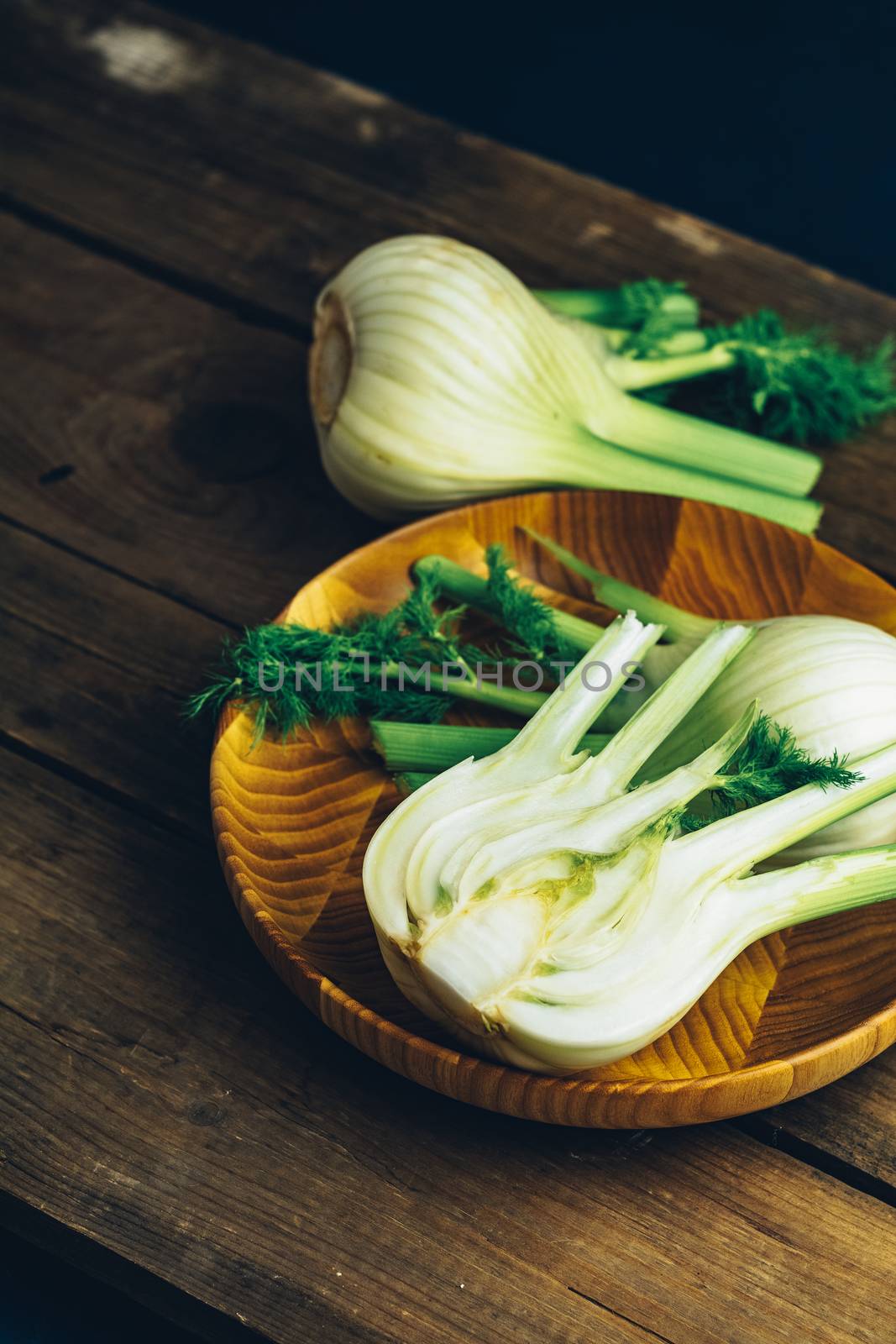 Fresh fennel bulbs in plate on wooden background. by ArtSvitlyna