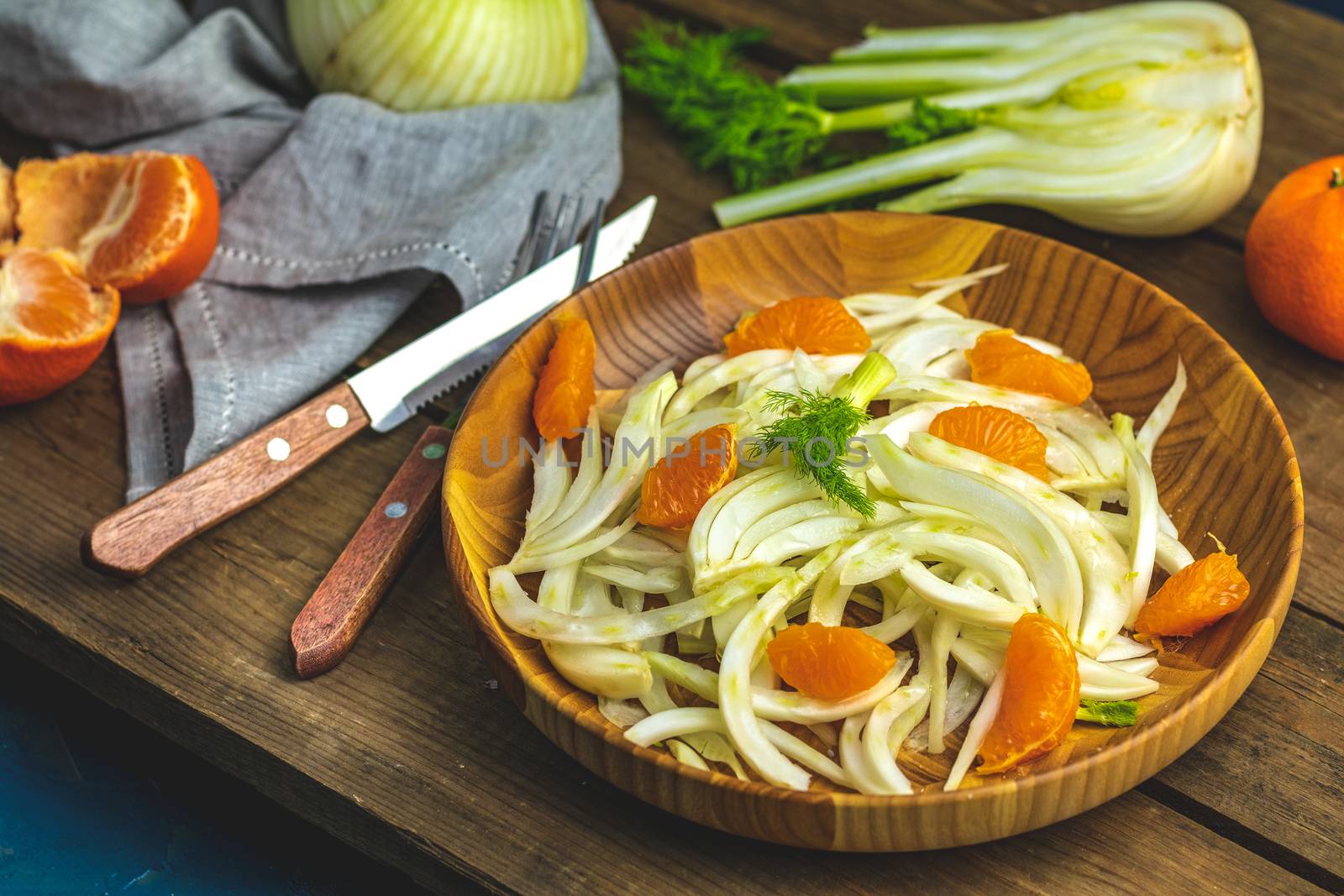 Traditional sicilian italian salad with fennel and tangerine. Fennel and orange citrus salad, on wooden plate. Modern, light, raw, veg cuisine. Winter salad.