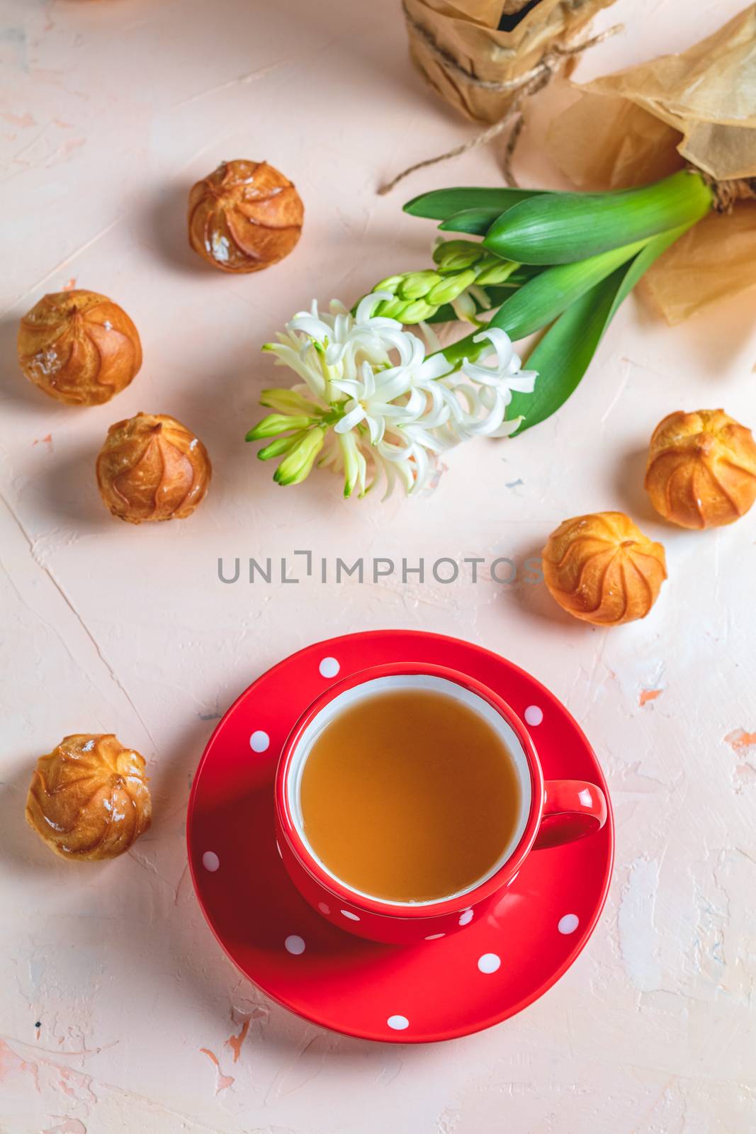 Red in white dotted cup of tea, profiteroles and hyacinths by ArtSvitlyna