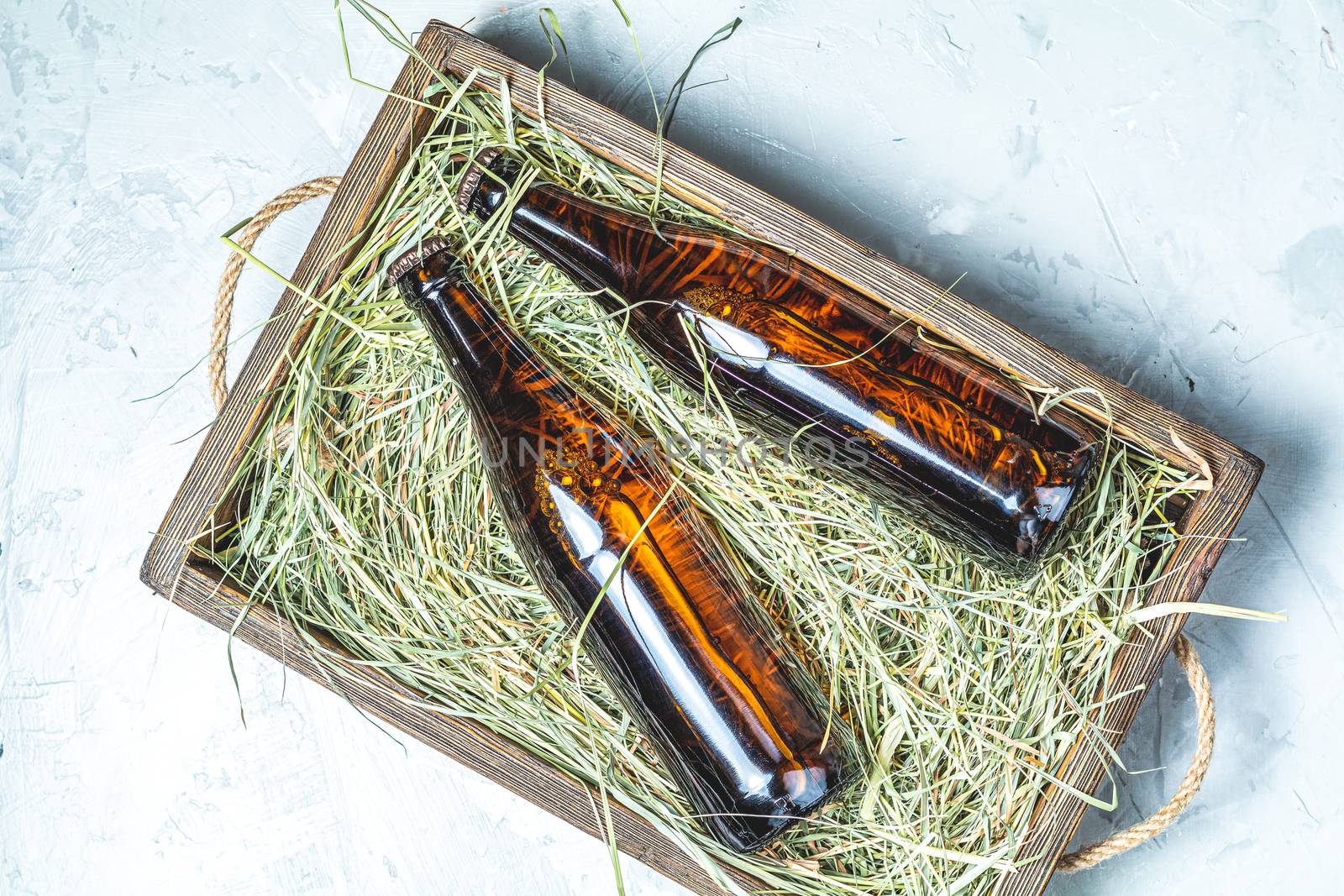 Craft beer with dried grass in wooden box on gray concrete surface background