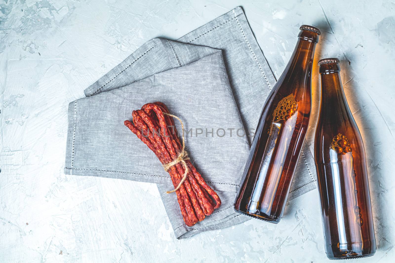 Craft beer with sausages kabanosi on gray concrete surface background, copy space for you text, rustic style.