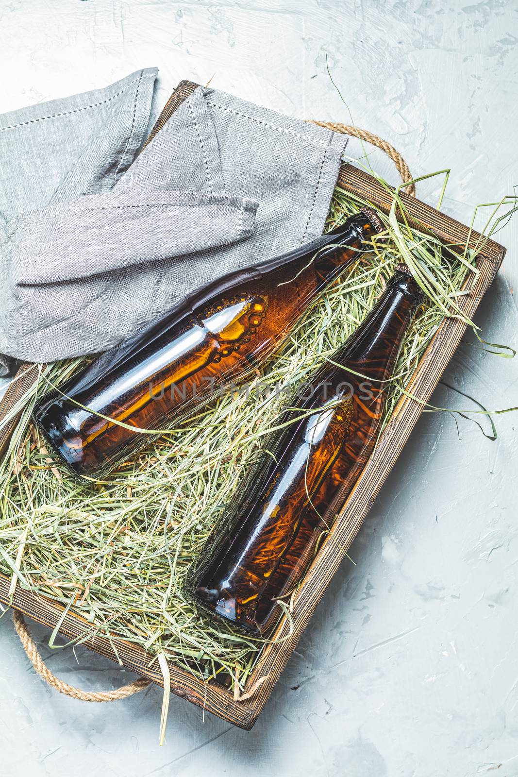 Craft beer with dried grass in wooden box on gray concrete surface background