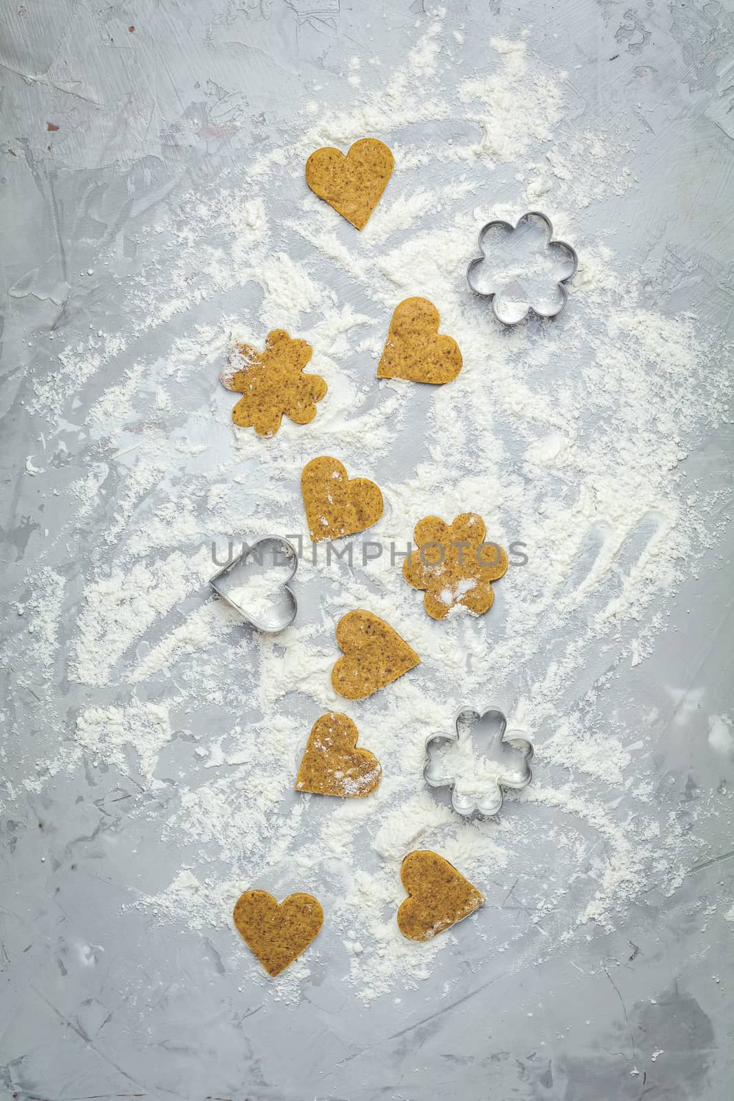 Raw homemade uncooked ginger cookies over light gray concrete surface. View from above, copy space for text, beautiful valentine day sweet food cooking card.