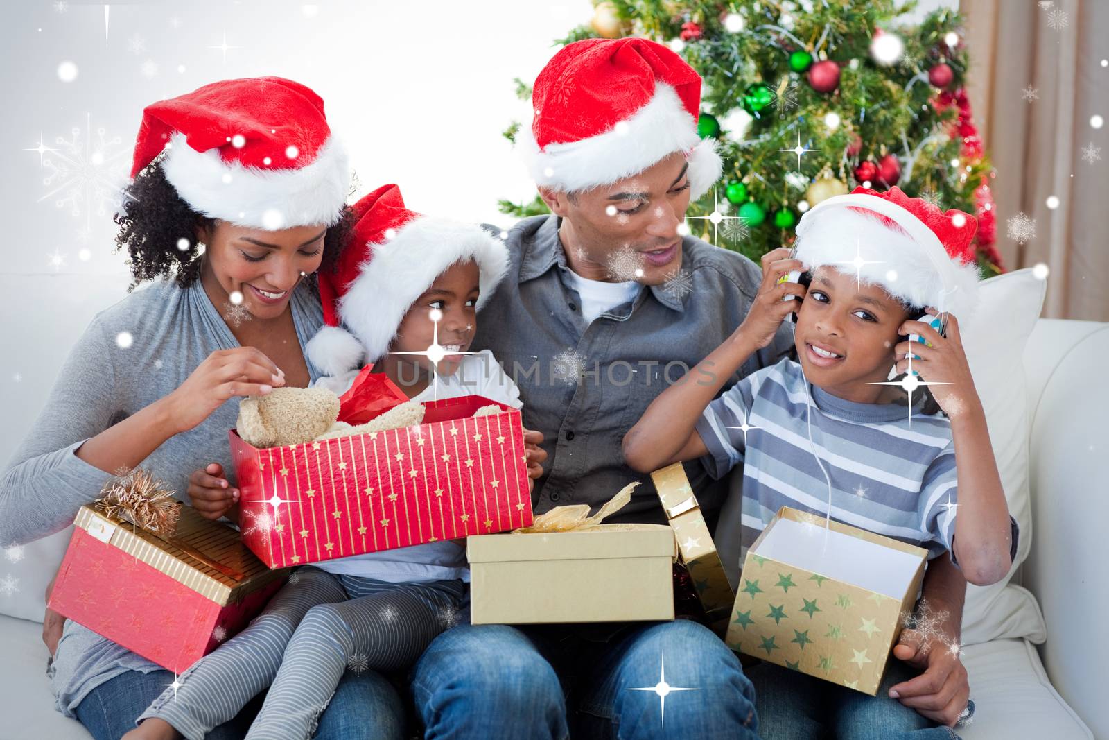 Happy family playing with Christmas presents against snow falling