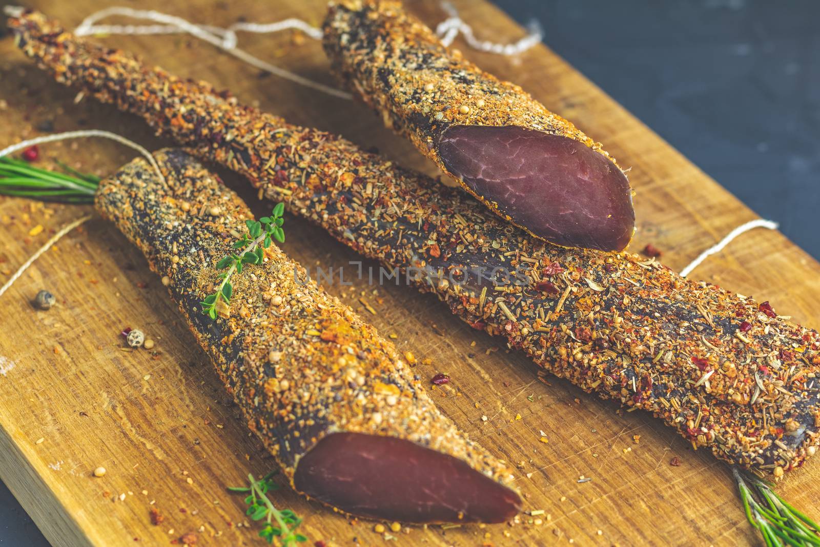 Jerky, basturma, dried meat beef, meat smoked jerky with spices on wooden cutting board, close up.