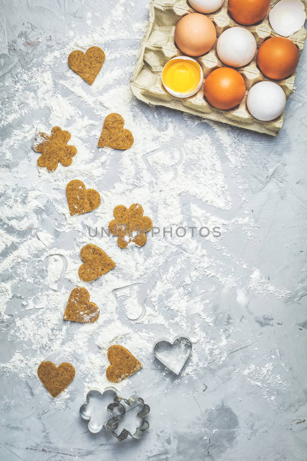 Raw homemade uncooked ginger cookies over light gray concrete surface. View from above, copy space for text, beautiful valentine day sweet food cooking card.