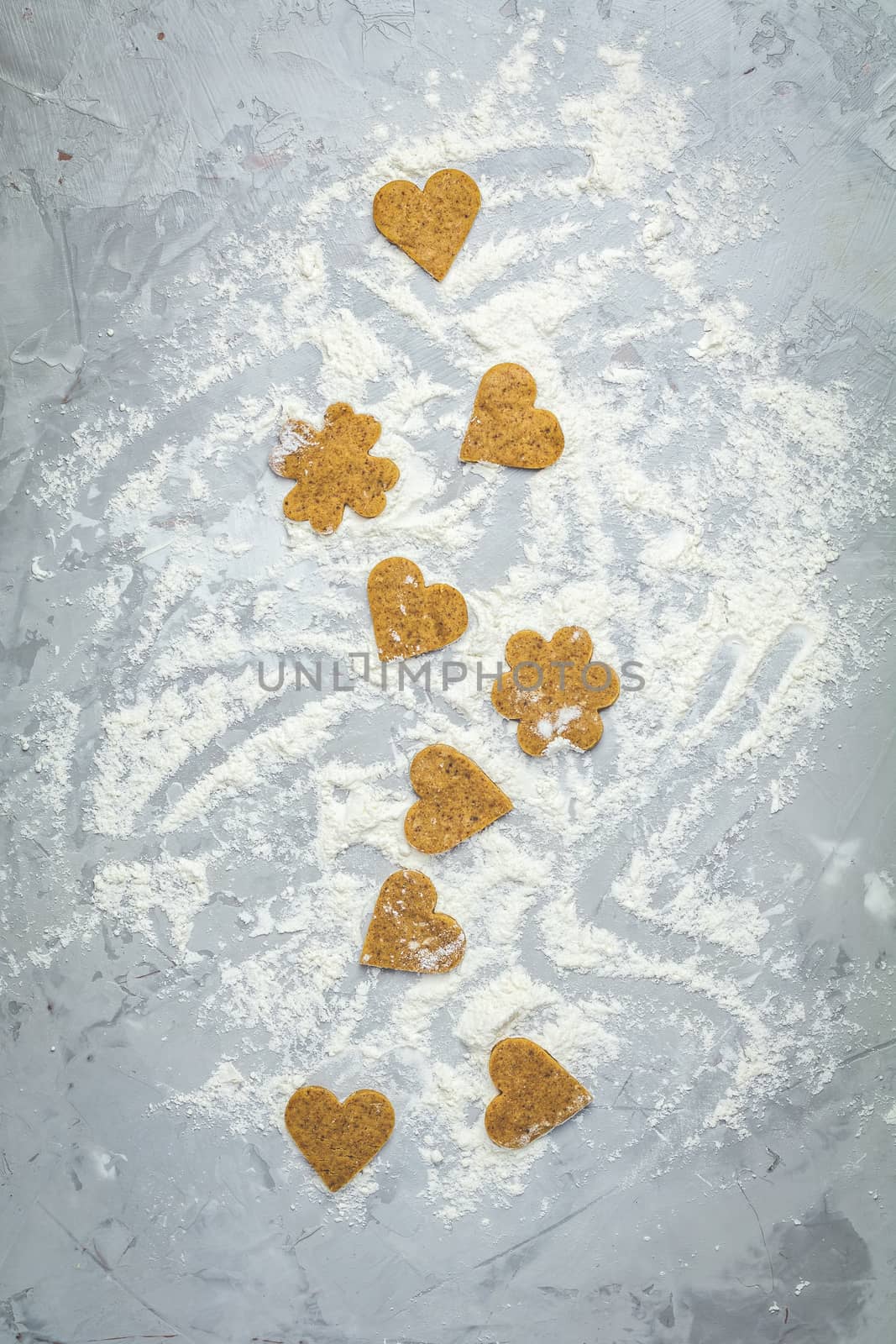 Raw homemade uncooked ginger cookies over light gray concrete surface. View from above, copy space for text, beautiful valentine day sweet food cooking card.
