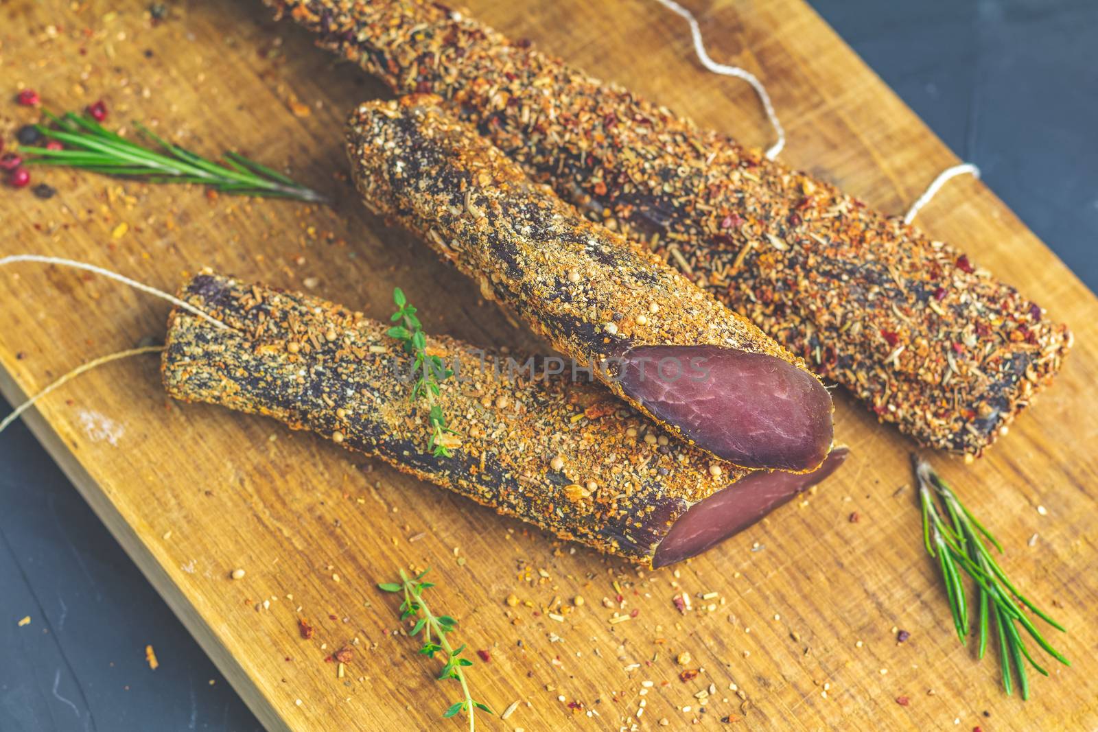 Jerky, basturma, dried meat beef, meat smoked jerky with spices on wooden cutting board, close up.