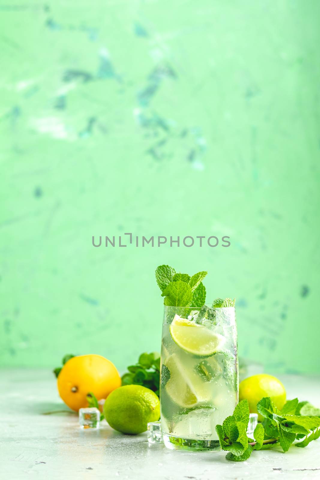 Mojito cocktail with lime and mint in highball glass on a gray and green concrete stone surface background. With copy space for your text