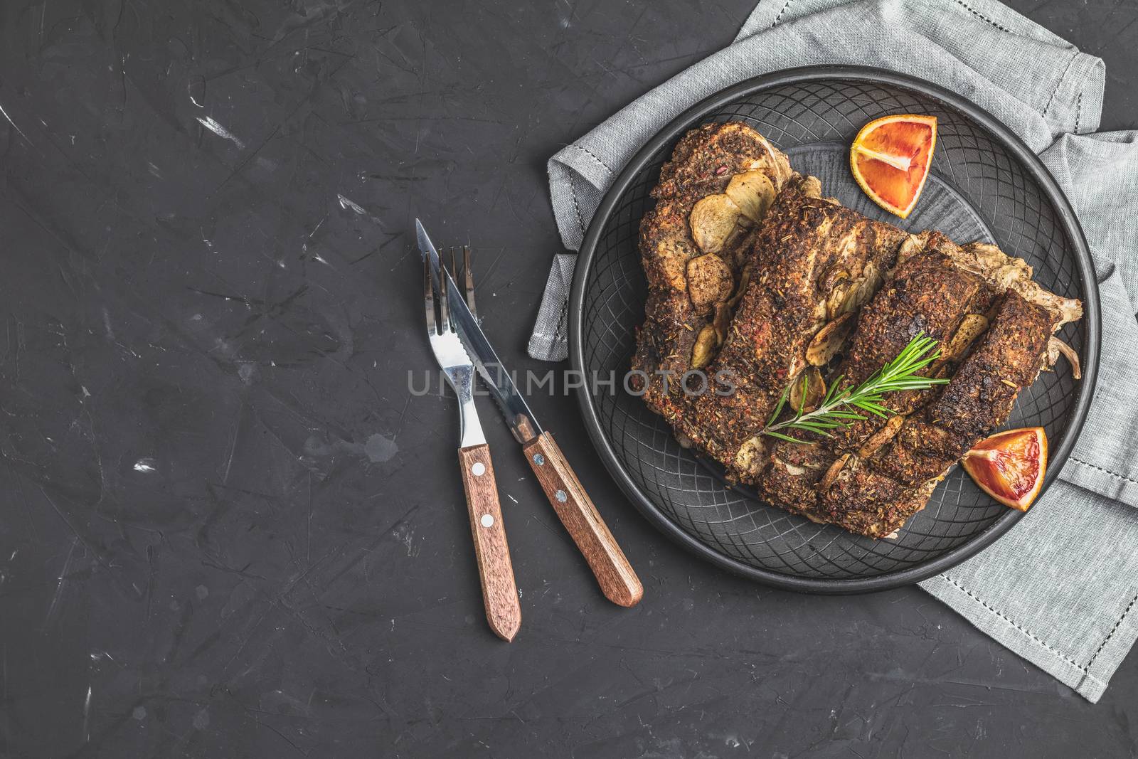 Delicious baked roast pork meat in black ceramic plate by ArtSvitlyna