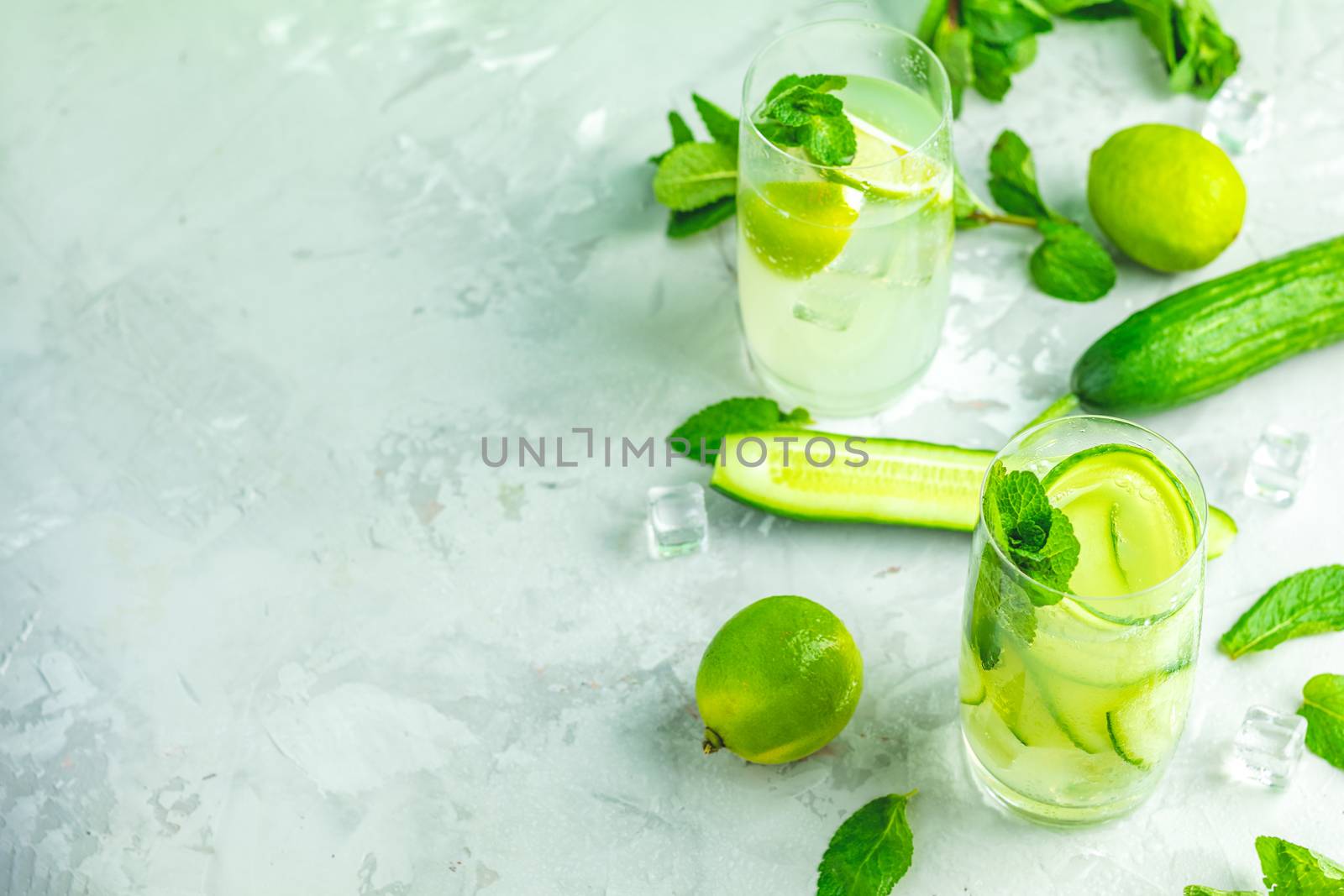 Detox cocktail of mint, cucumber and lemon and mojito cocktail with lime and mint in highball glasses on a gray concrete stone surface background. With copy space for your text