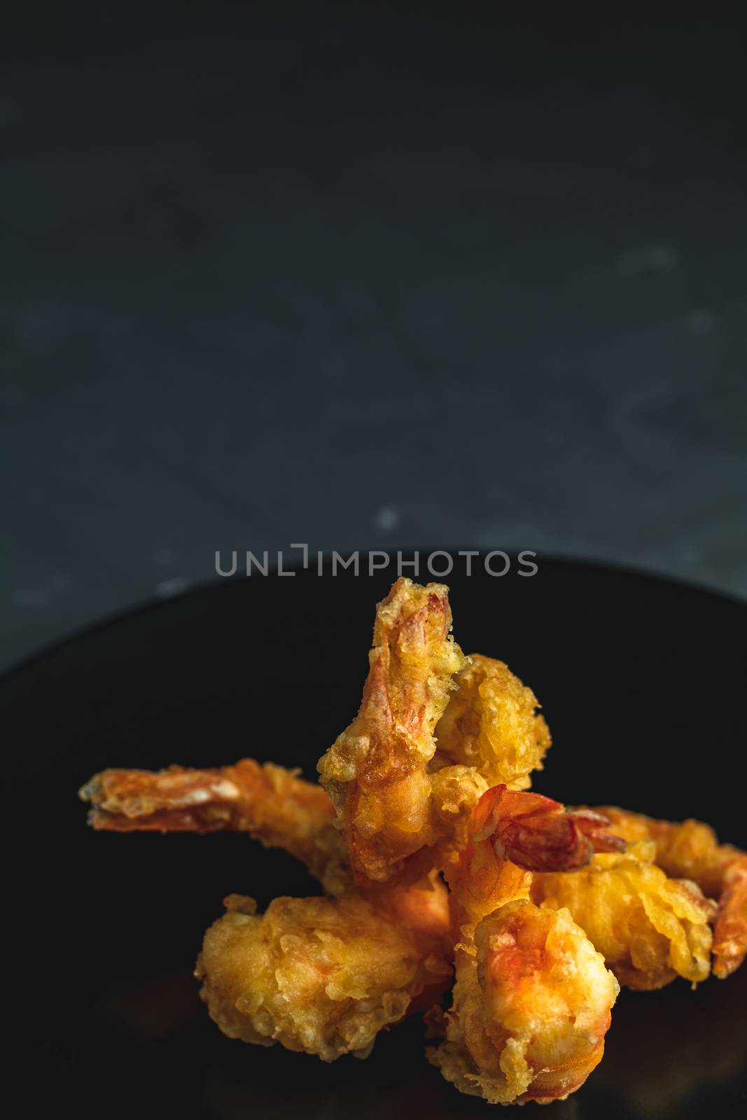Fried Shrimps tempura in black plate on dark concrete surface by ArtSvitlyna