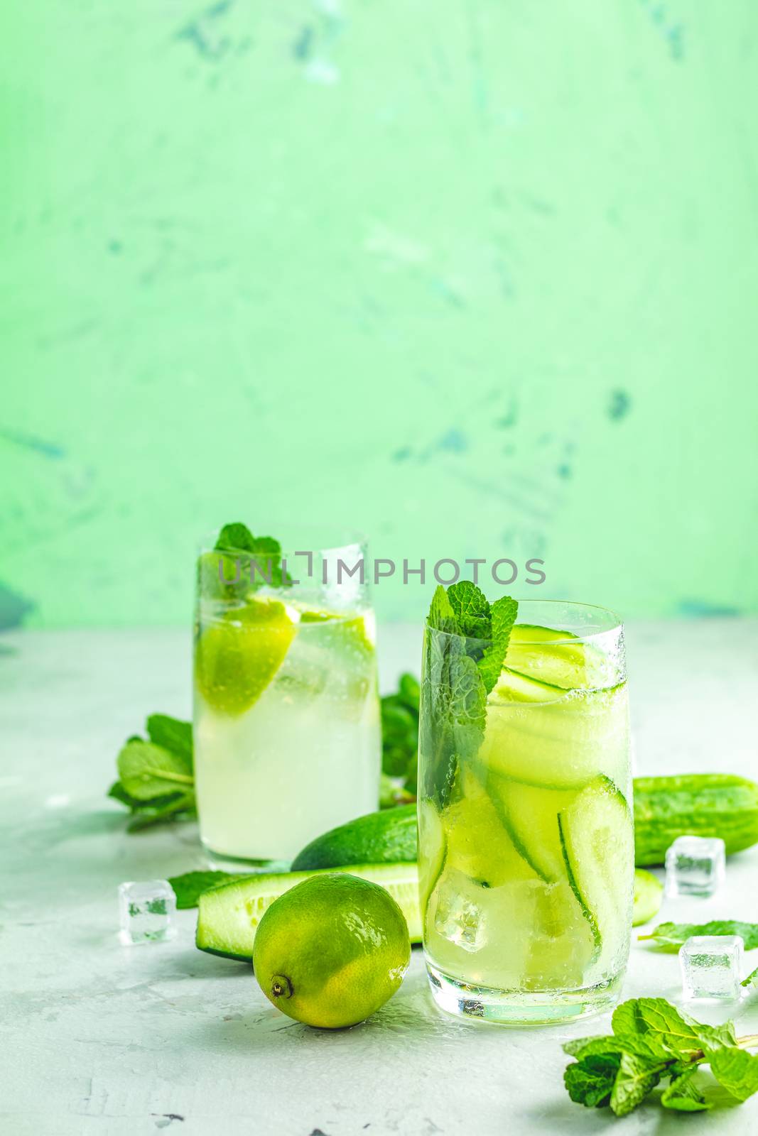 Detox cocktail of mint, cucumber and lemon and mojito cocktail with lime and mint in highball glasses on a gray concrete stone surface background. With copy space for your text