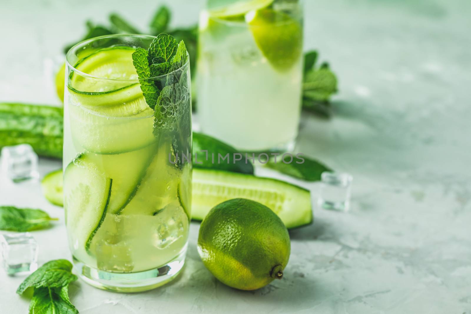 Detox cocktail of mint, cucumber and lemon and mojito cocktail with lime and mint in highball glasses on a gray concrete stone surface background. With copy space for your text