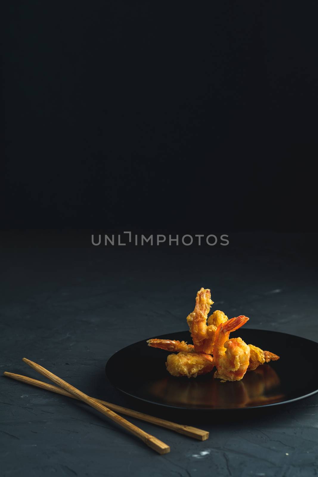 Fried Shrimps tempura in black plate on dark concrete surface by ArtSvitlyna