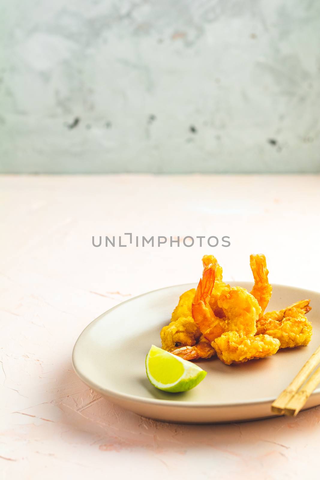 Fried Shrimps tempura in light plate on pink or peach concrete surface background. Copy space for you text. Seafood tempura dish of traditional asian cuisine.