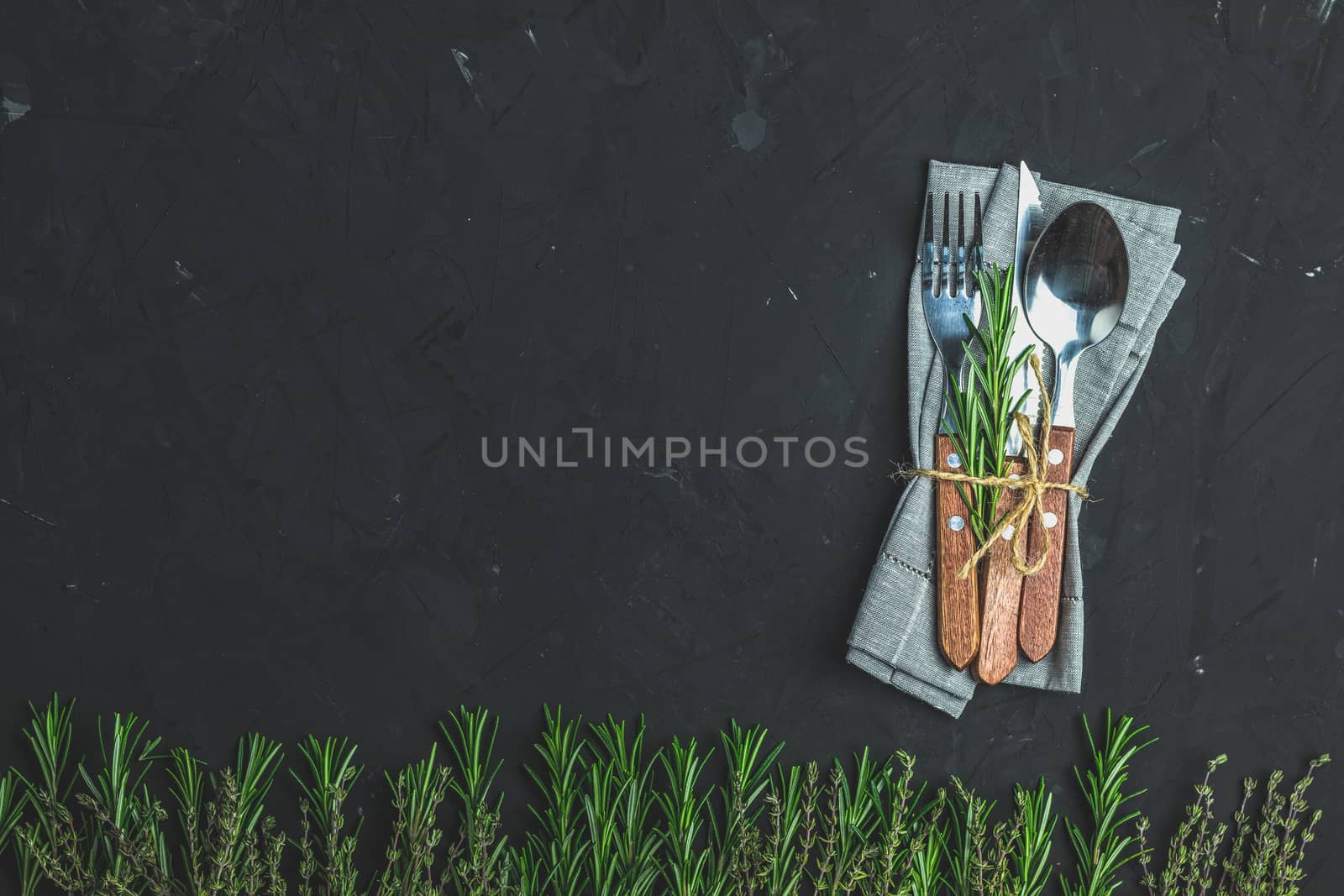 Rustic vintage set of cutlery knife, spoon, fork. Black stone concrete surface background. Top view, copy space.