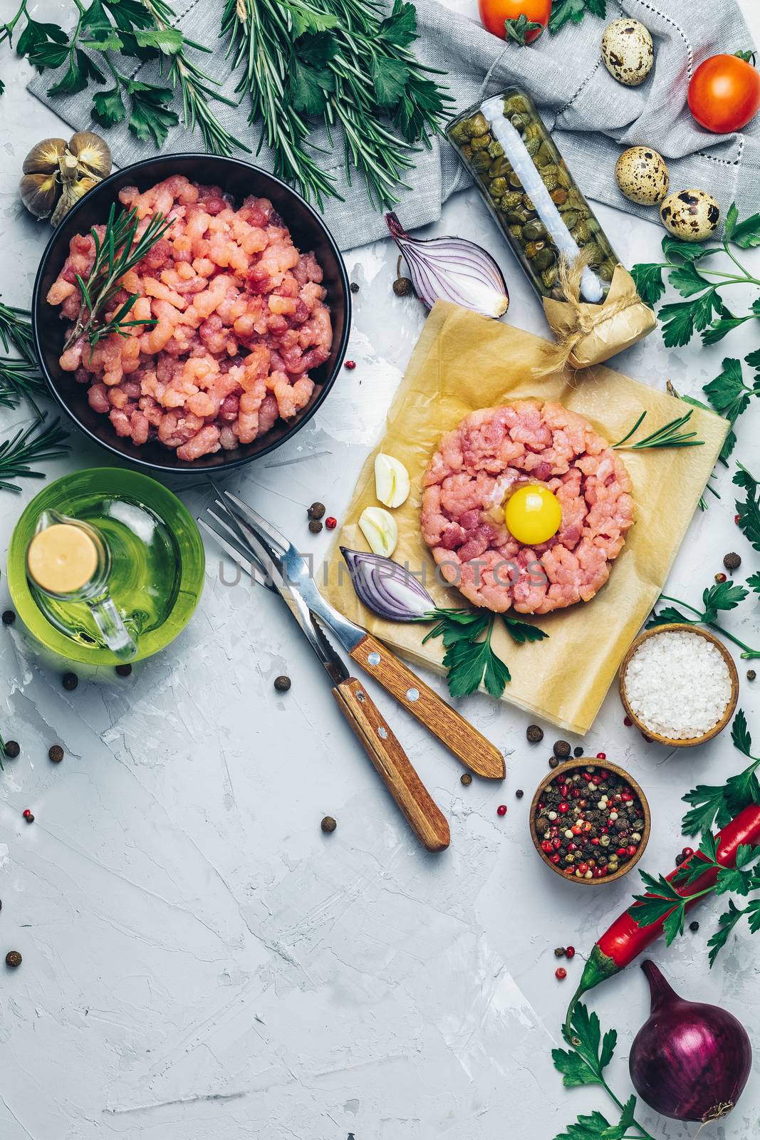 Healthy food, cooking concept. Homemade raw organic minced beef meat and steak tartare with yolk with vegetables on light gray stone concrete textured surface background. Copy space background, top view flat lay.