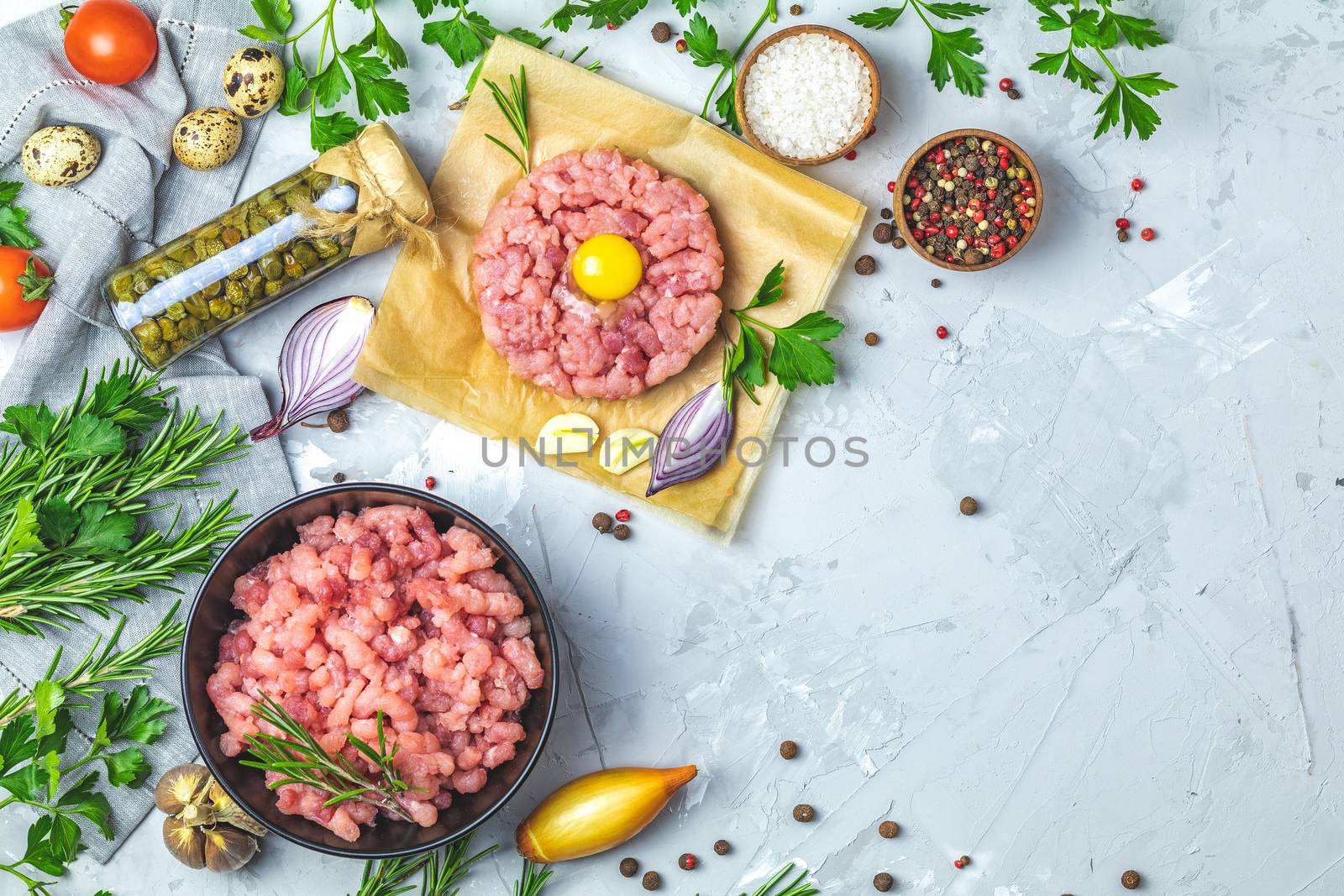 Healthy food, cooking concept. Homemade raw organic minced beef meat and steak tartare with yolk with vegetables on light gray stone concrete textured surface background. Copy space background, top view flat lay.