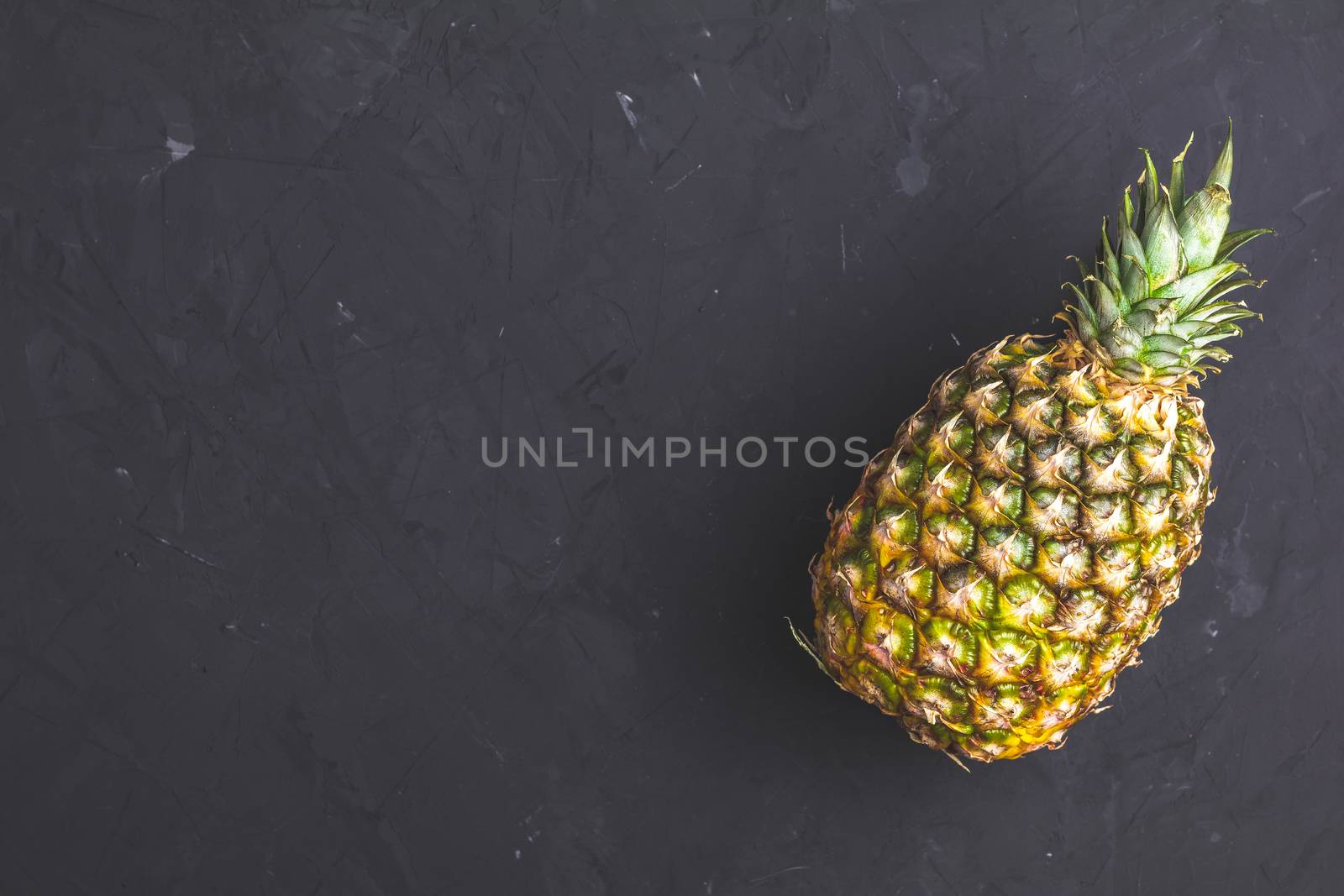 Pineapple on black stone concrete textured surface background. Top view with copy space for your text.