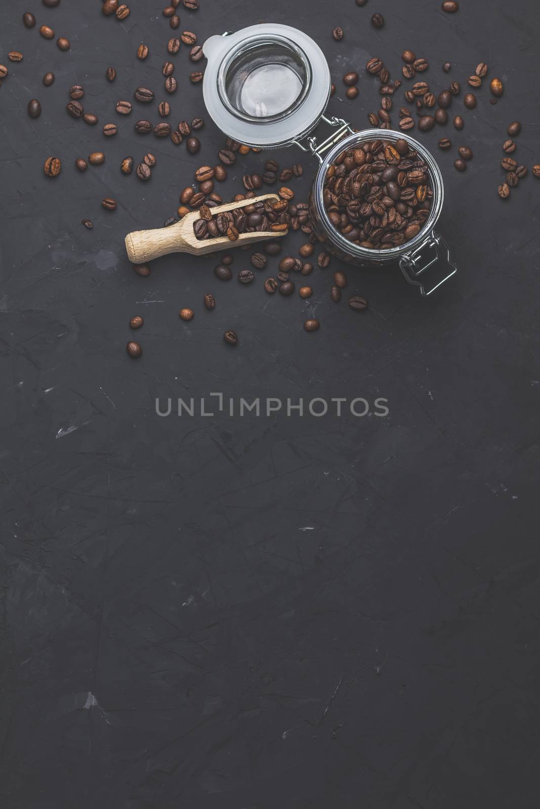 Glass jar with roasted beans on black stone concrete surface by ArtSvitlyna