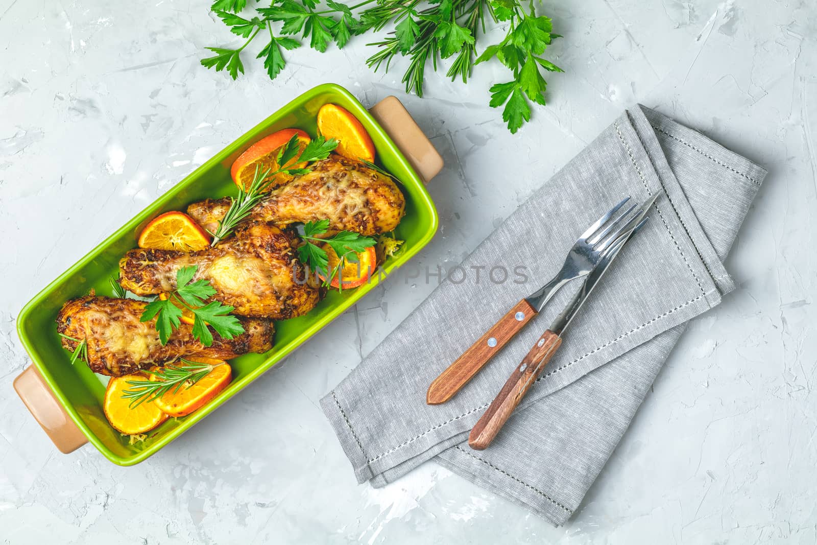 Baked chicken drumstick in a green dish with orange and rosemary by ArtSvitlyna