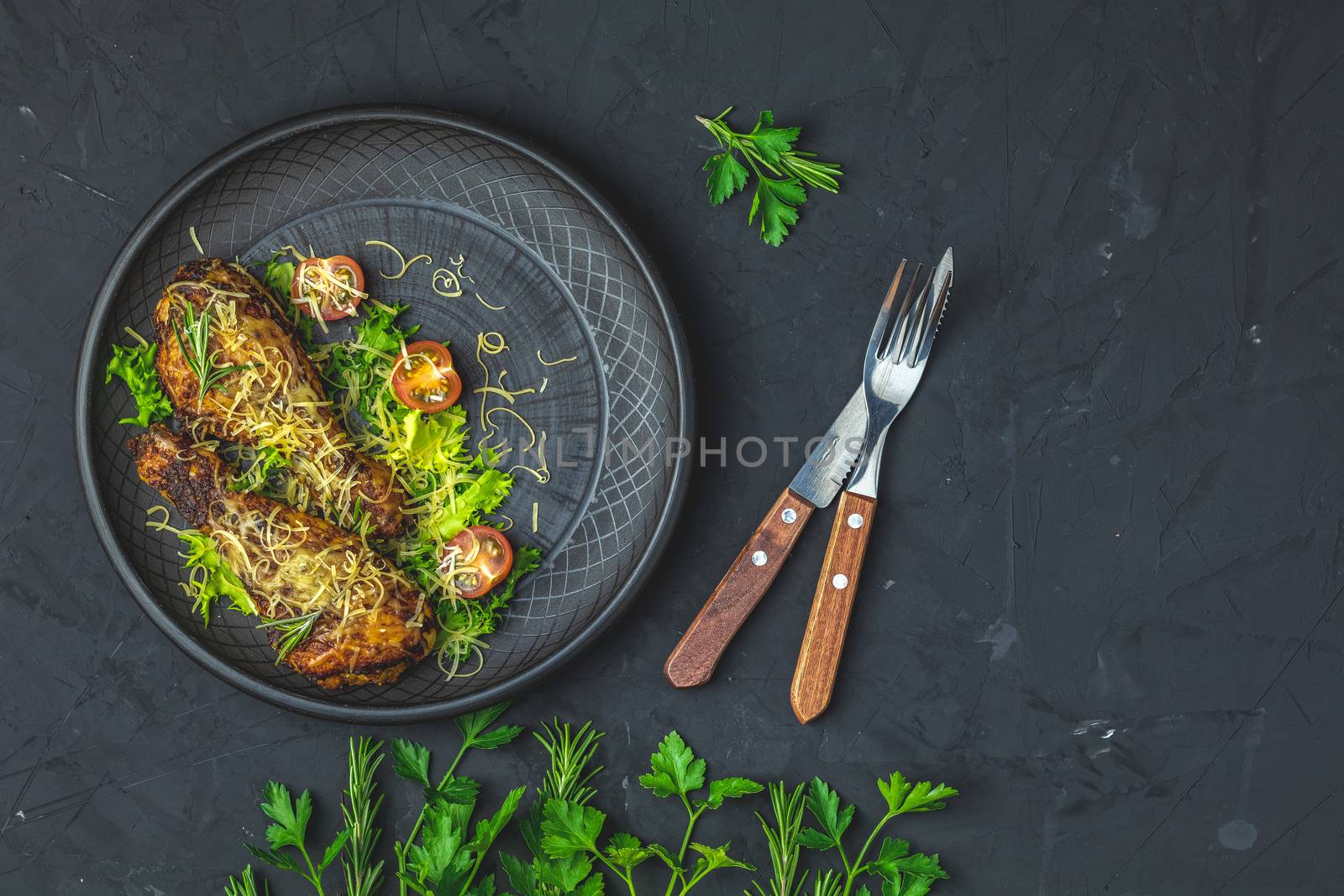 Baked chicken drumstick in a black ceramic plate by ArtSvitlyna