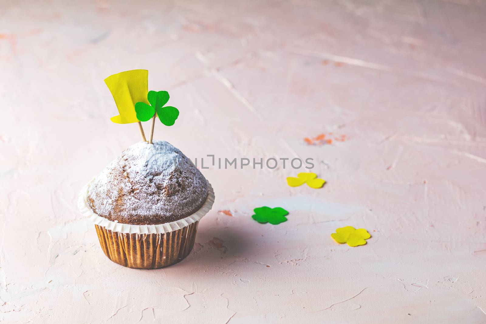 Tasty delicious homemade muffin on light pink living coral stone concrete surface with knitting hearts, copy space. Sweet food for Saint Patrick day.