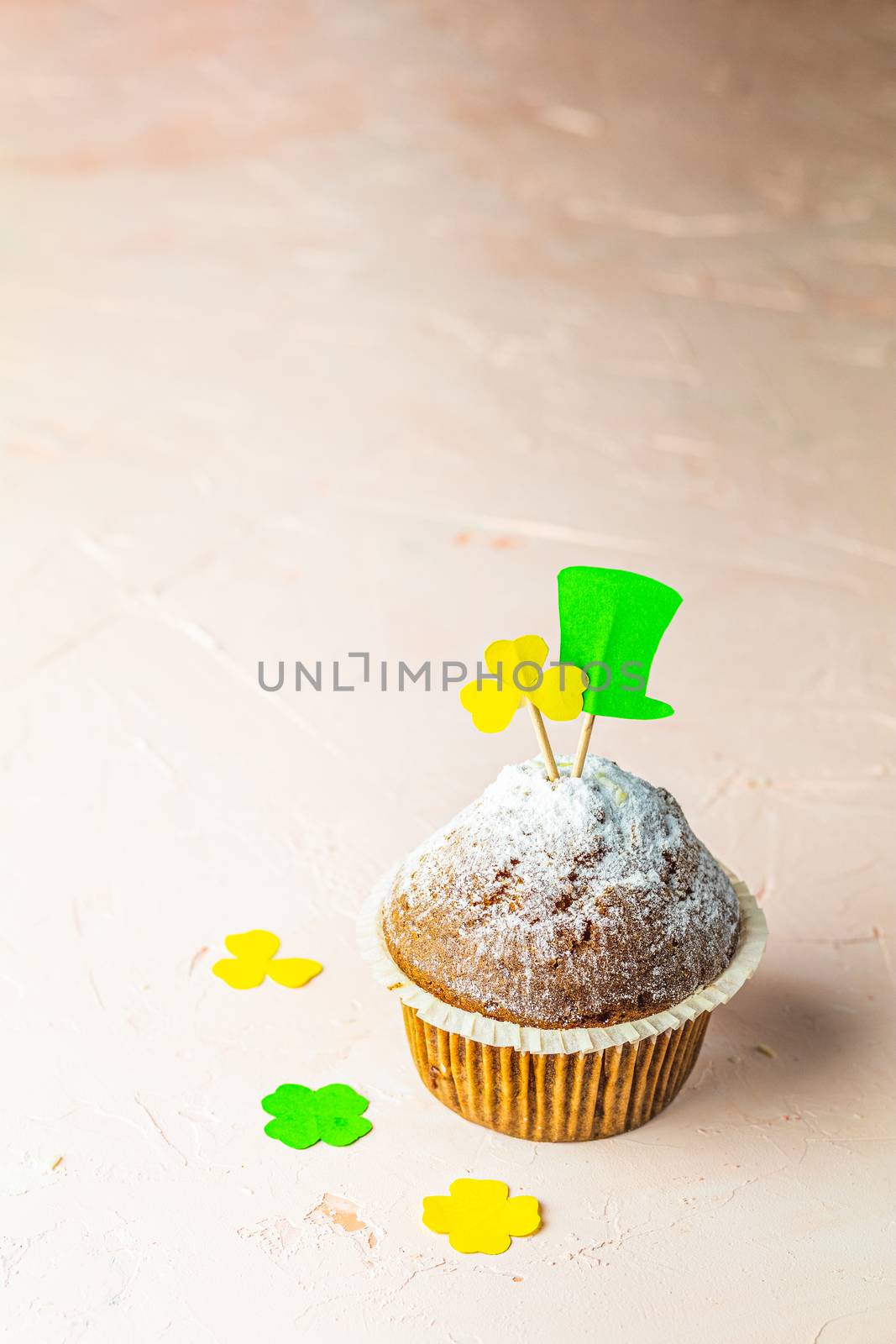 Tasty delicious homemade muffin on light pink living coral stone concrete surface with knitting hearts, copy space. Sweet food for Saint Patrick day.