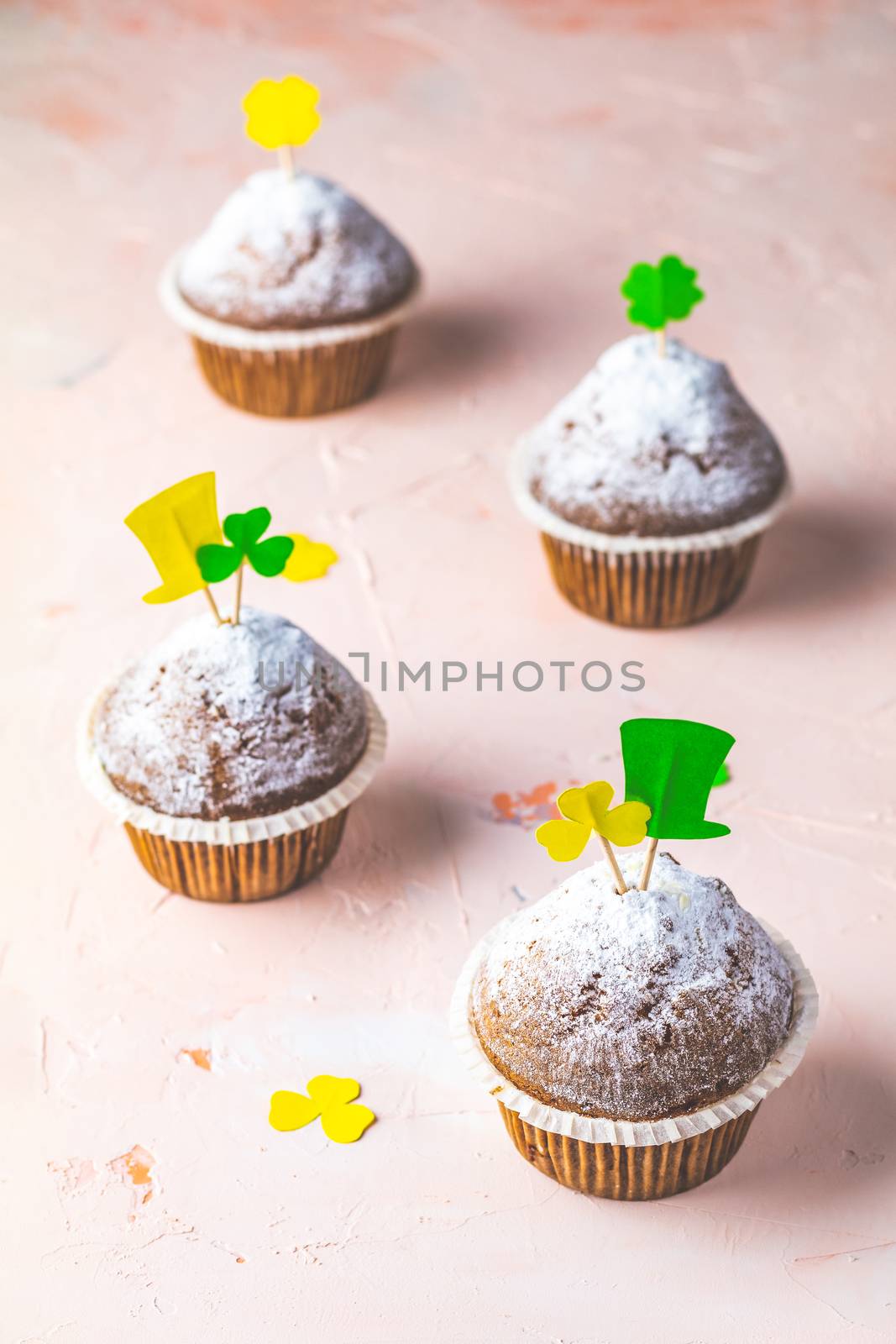 Tasty delicious homemade muffin on light pink living coral stone concrete surface with knitting hearts, copy space. Sweet food for Saint Patrick day.