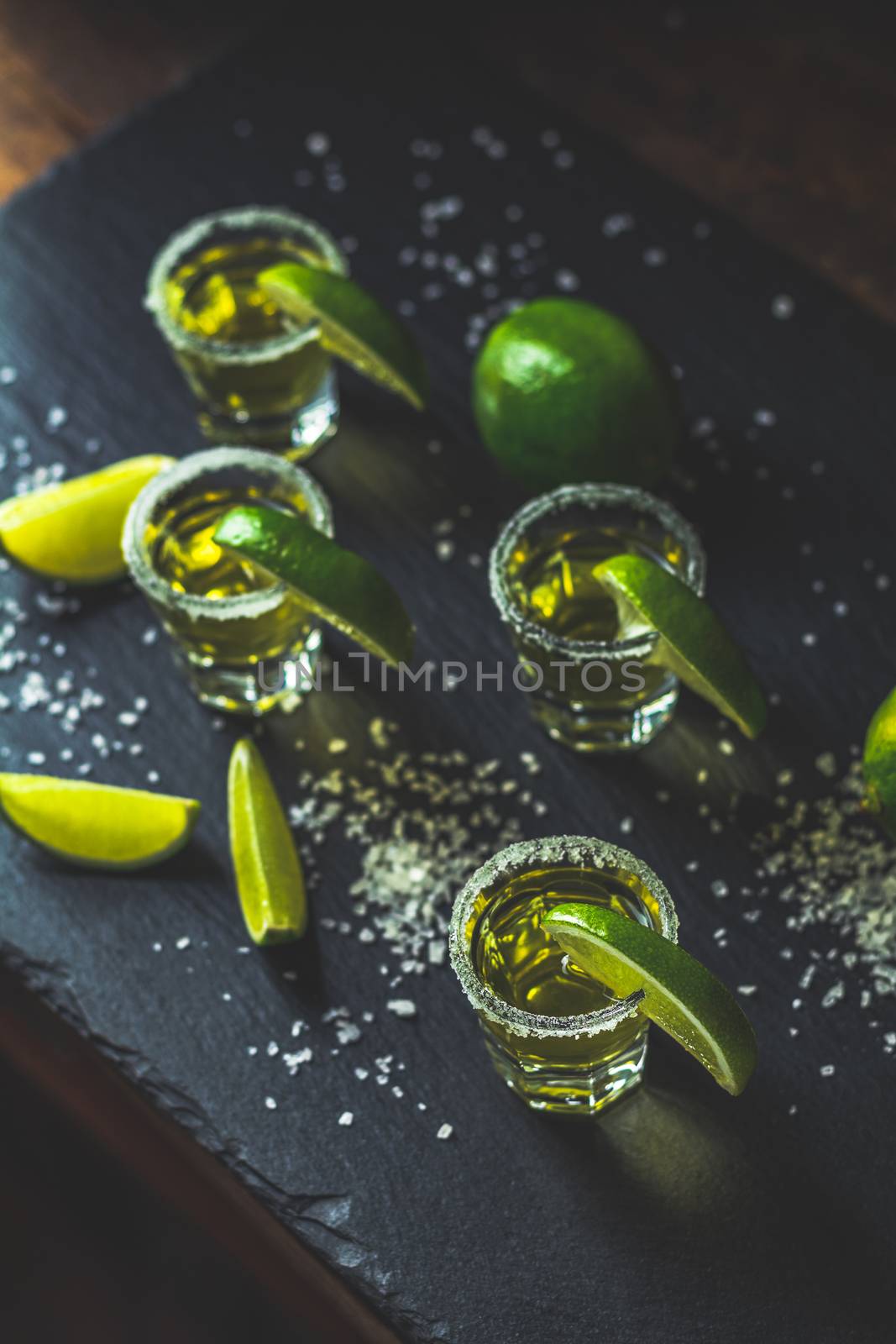 Mexican Gold Tequila shot  with lime and salt on black stone table surface, selective focus, shallow depth of the field, copy space.