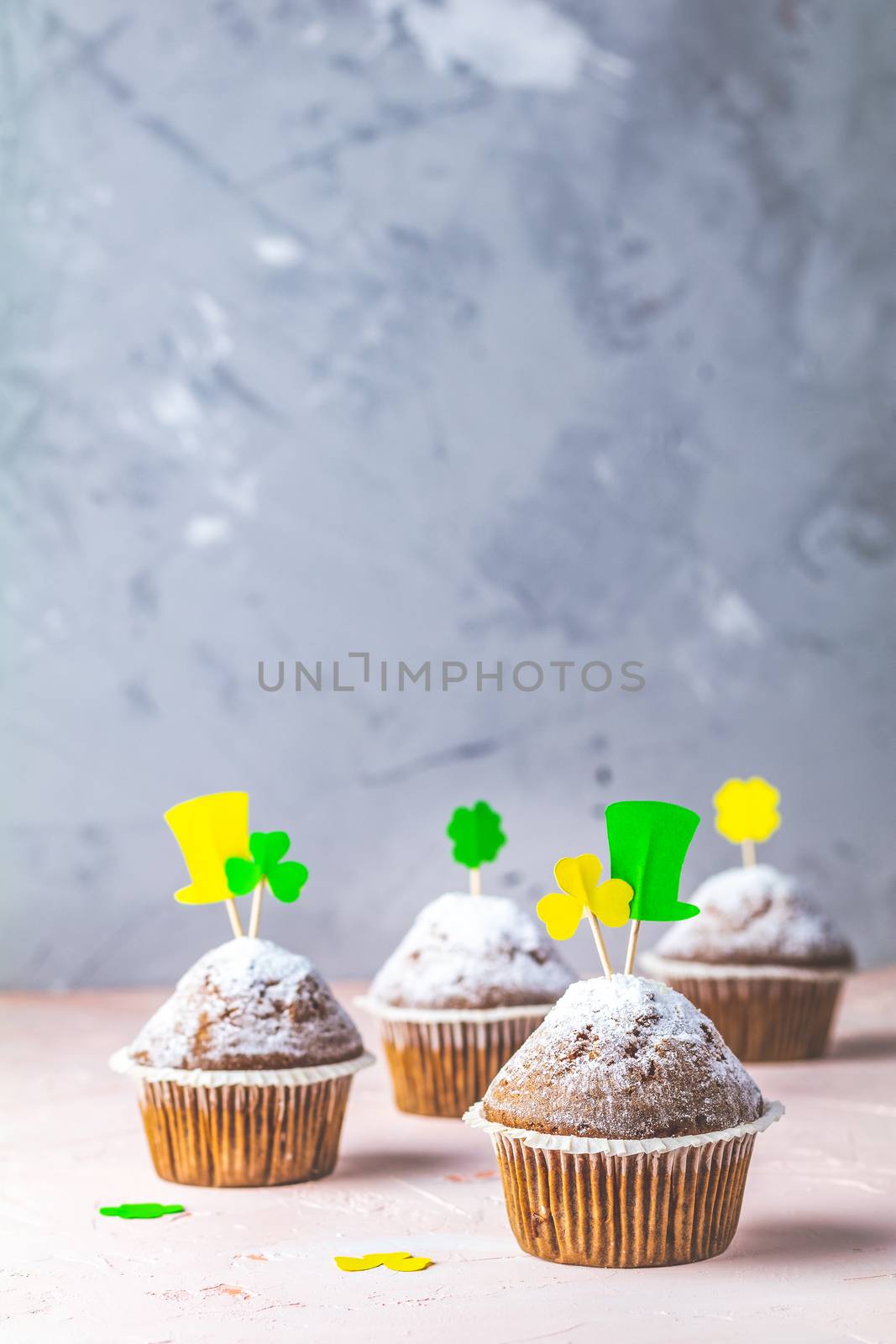 Tasty delicious homemade muffins on light pink living coral stone concrete surface with holiday attributes, copy space. Beautiful sweet food concept for Saint Patrick day.