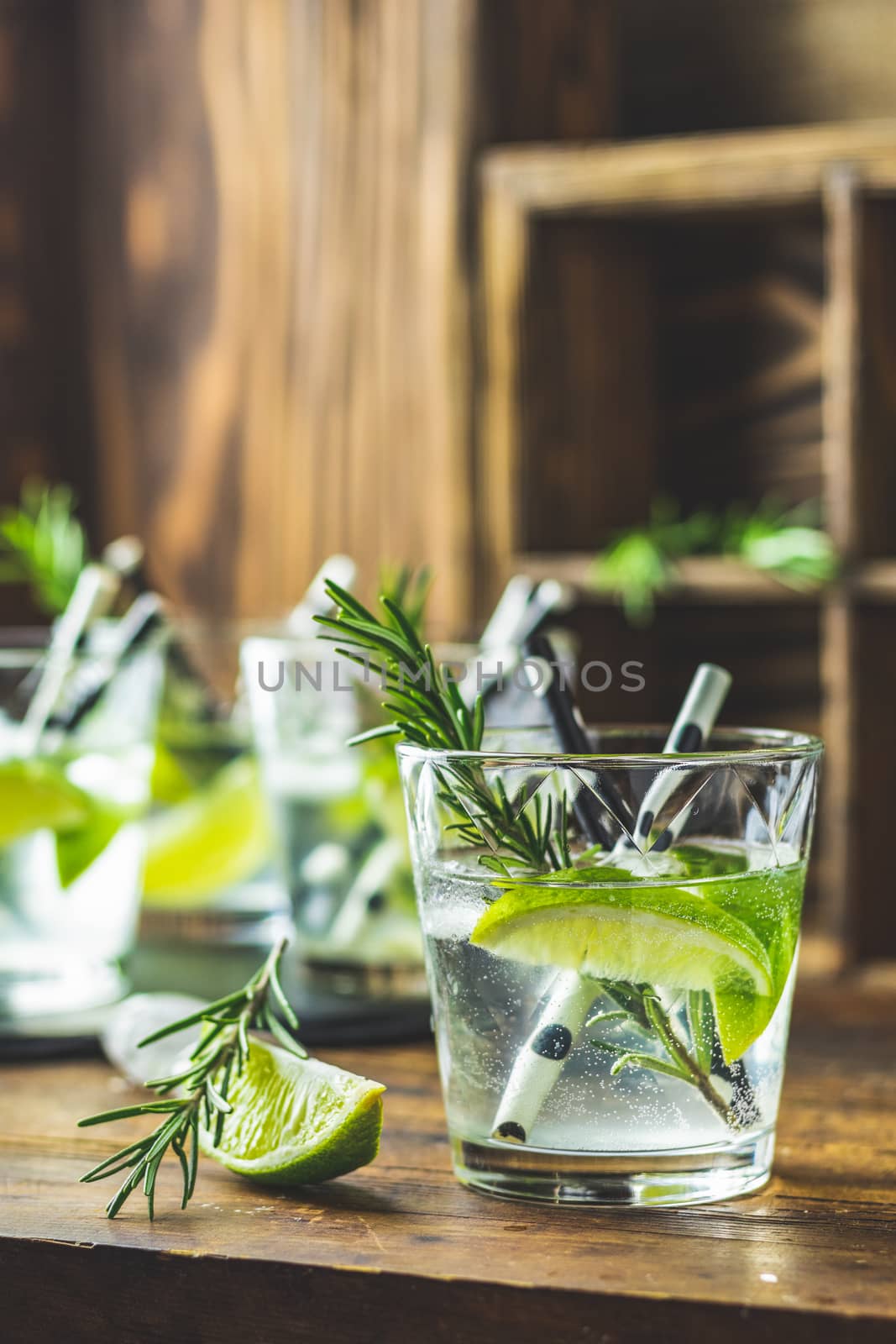 Fresh cocktail with lime, ice and rosemary, mojito cocktail in a bur on a rustic table, selective focus, shallow depth of the field.