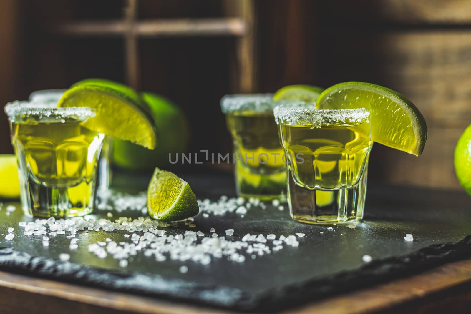 Mexican Gold Tequila shot with lime and salt on black stone table surface, selective focus, shallow depth of the field, copy space.