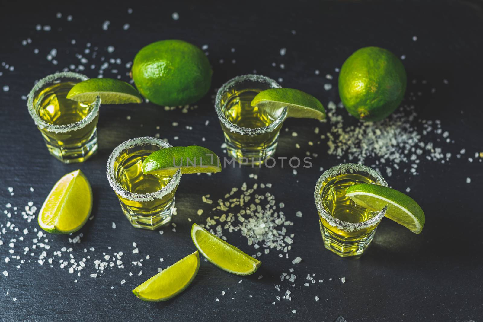 Mexican Gold Tequila shot with lime and salt on black stone table surface, selective focus, shallow depth of the field, copy space.