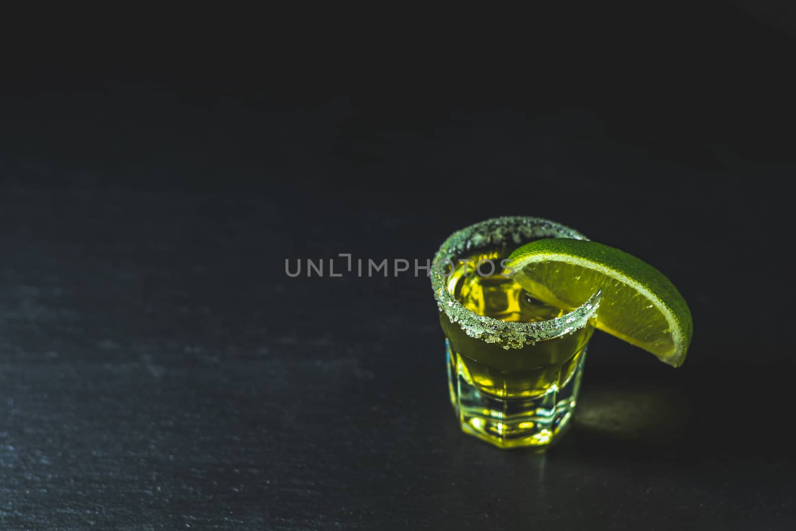 Mexican Gold Tequila shot with lime and salt on black stone tabl by ArtSvitlyna