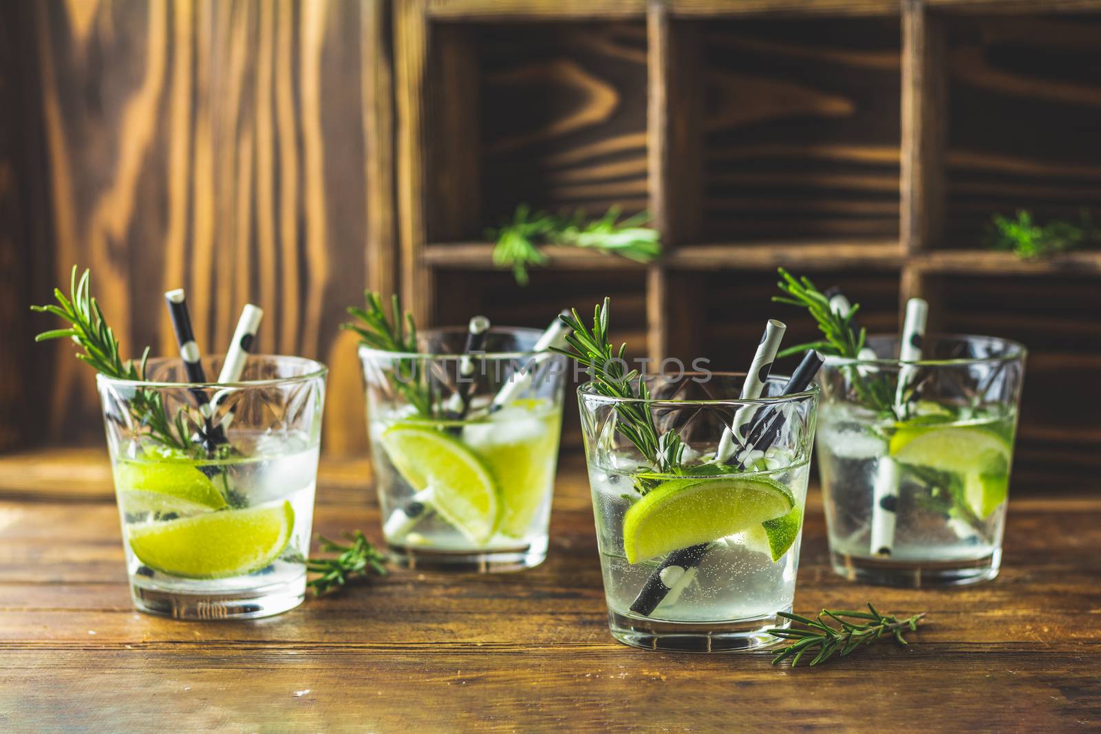 Fresh cocktail with lime, ice and rosemary, mojito cocktail in a bur on a rustic table, selective focus, shallow depth of the field.